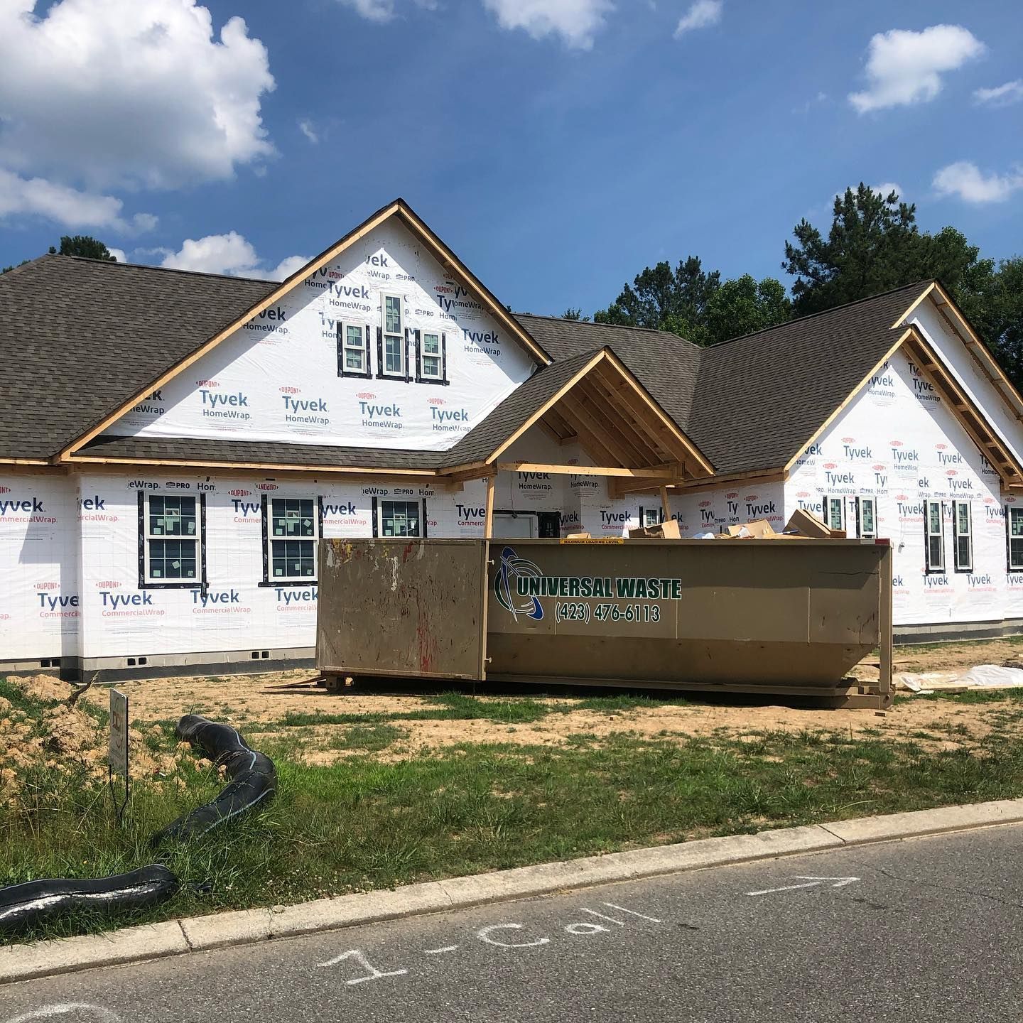 A large house under construction with a large dumpster in front of it