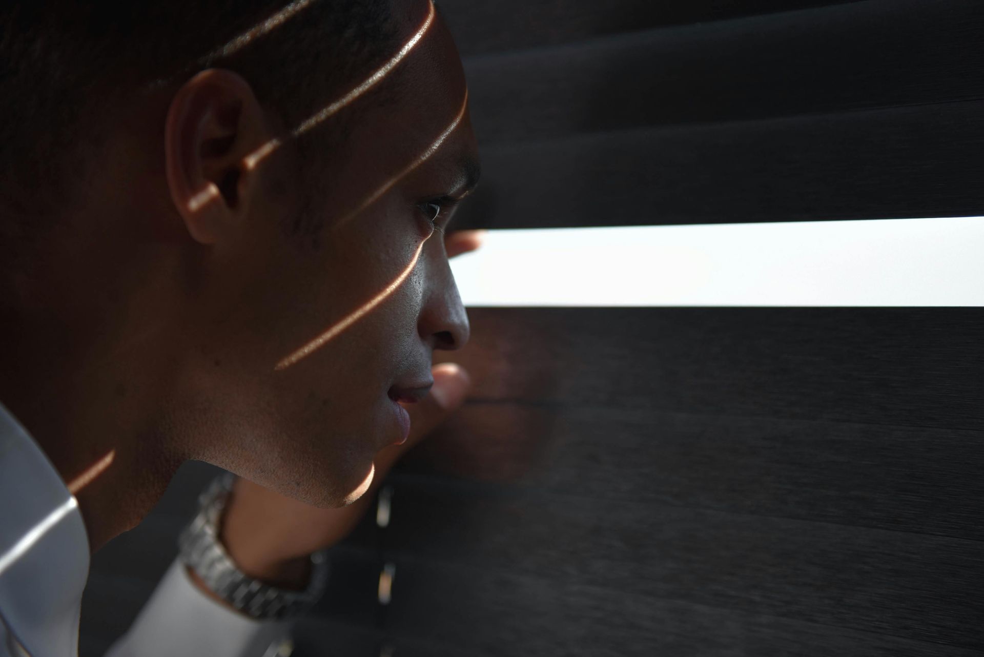 Profile of a person in a dark room, lit by a bright horizontal light strip