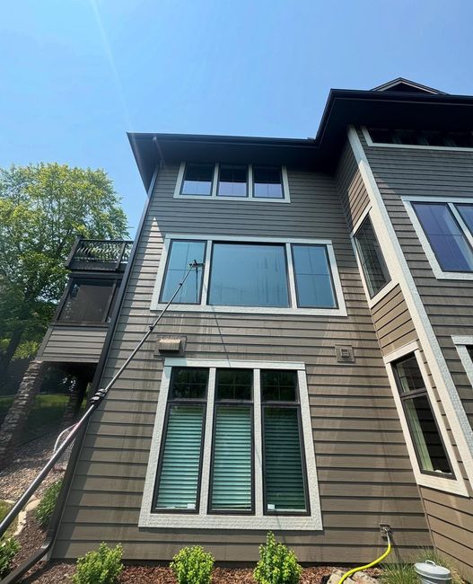 Tall gray townhouse exterior with large windows and a blue sky above