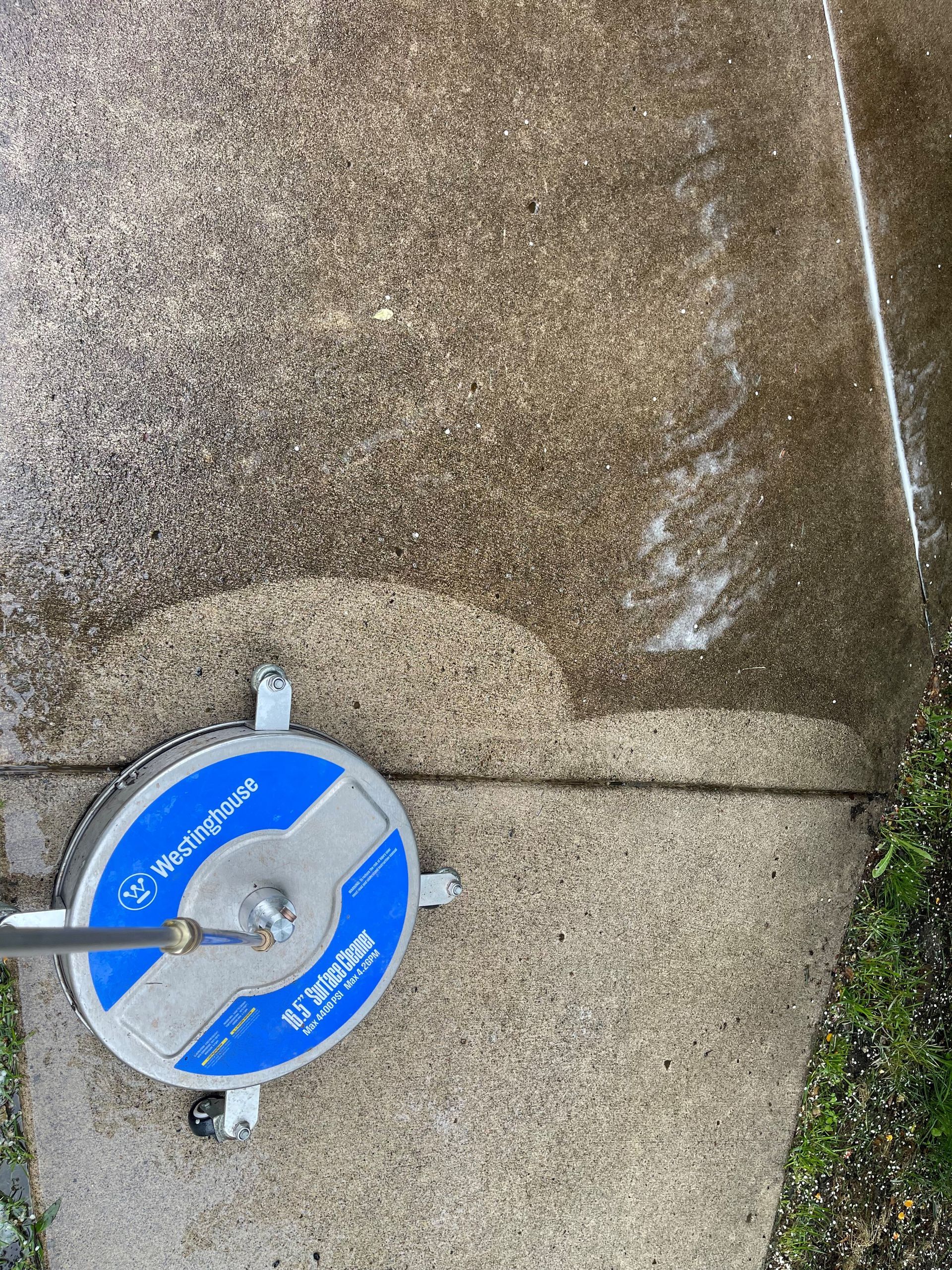 Blue valve wheel on a concrete surface with a pipe handle attached, near a crack and grass edge
