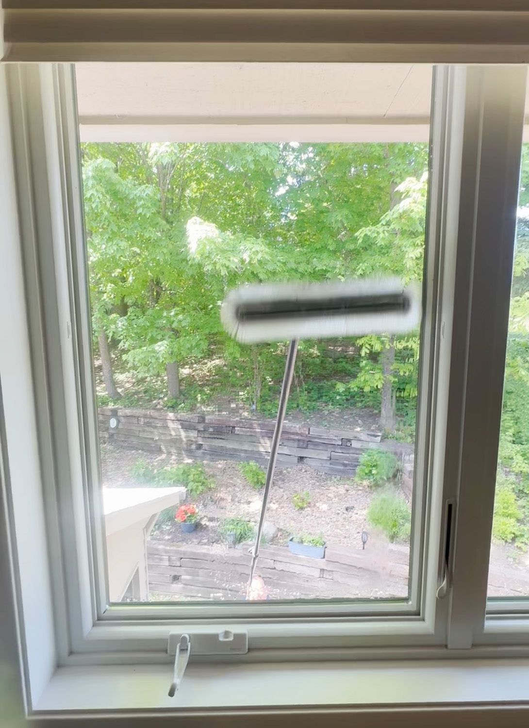 Open window with a garden and trees outside, plus a blurred white object near the top.
