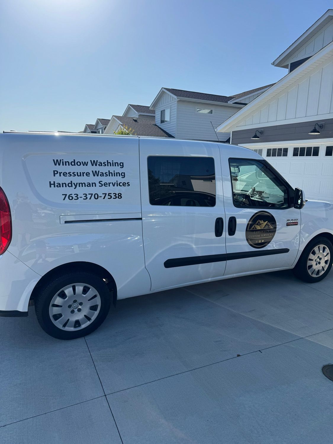 White service van with company logo and text parked in a driveway outside a house.