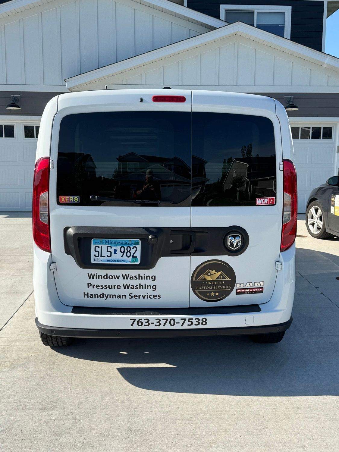 White service van with company logos parked in front of a garage