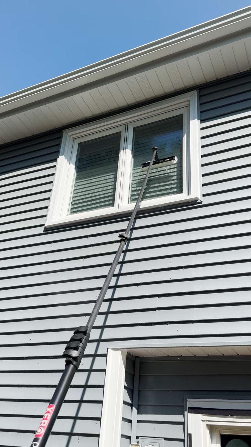 Ladder leaning to second-story window on gray house exterior