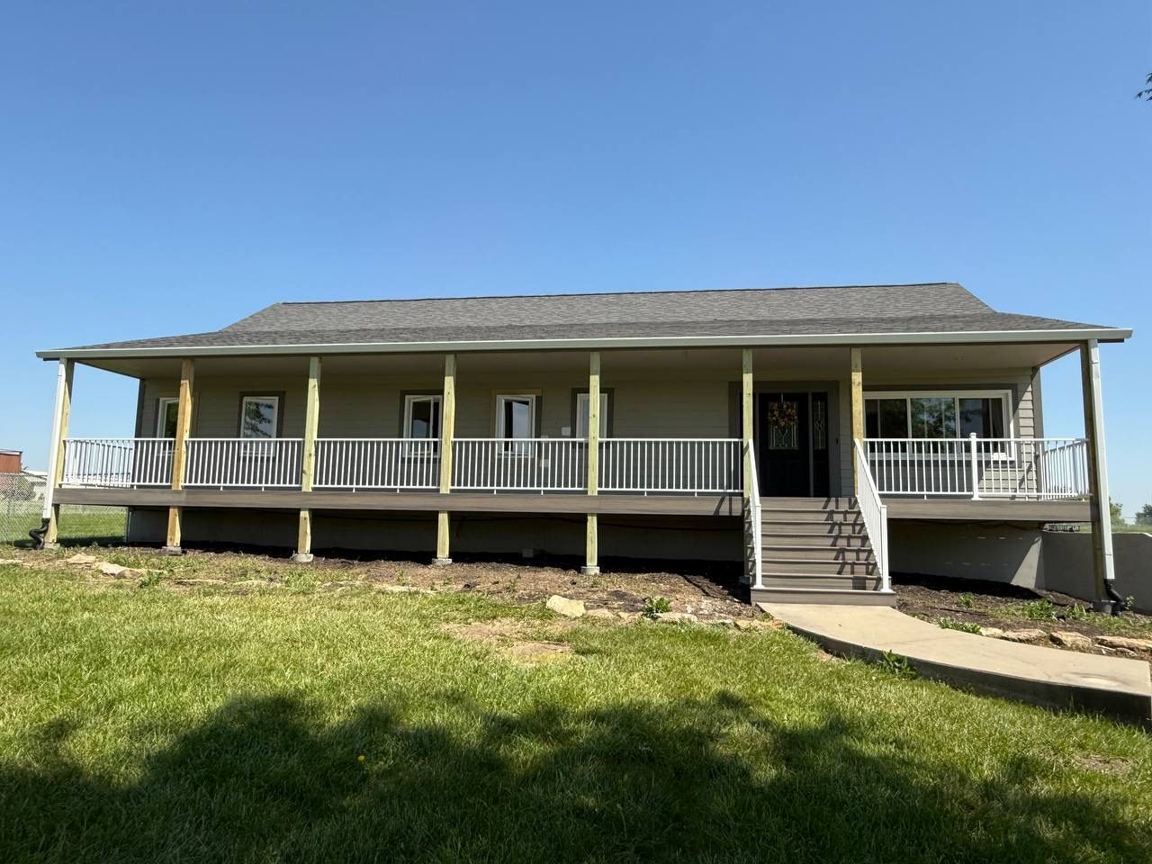 Wide front porch on a single-story gray house under a clear blue sky