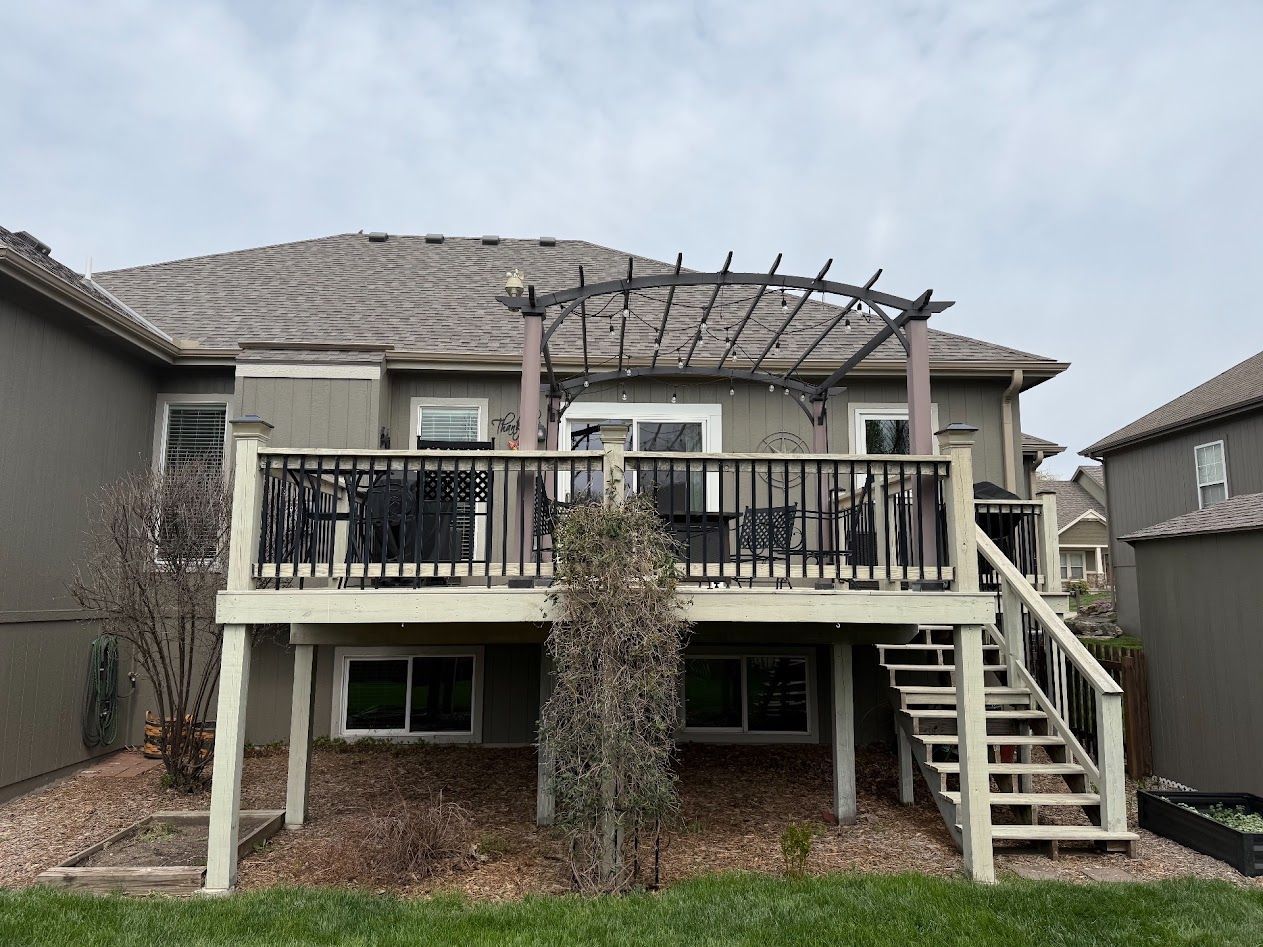 Two-story house with a deck, stairs, and pergola in the backyard