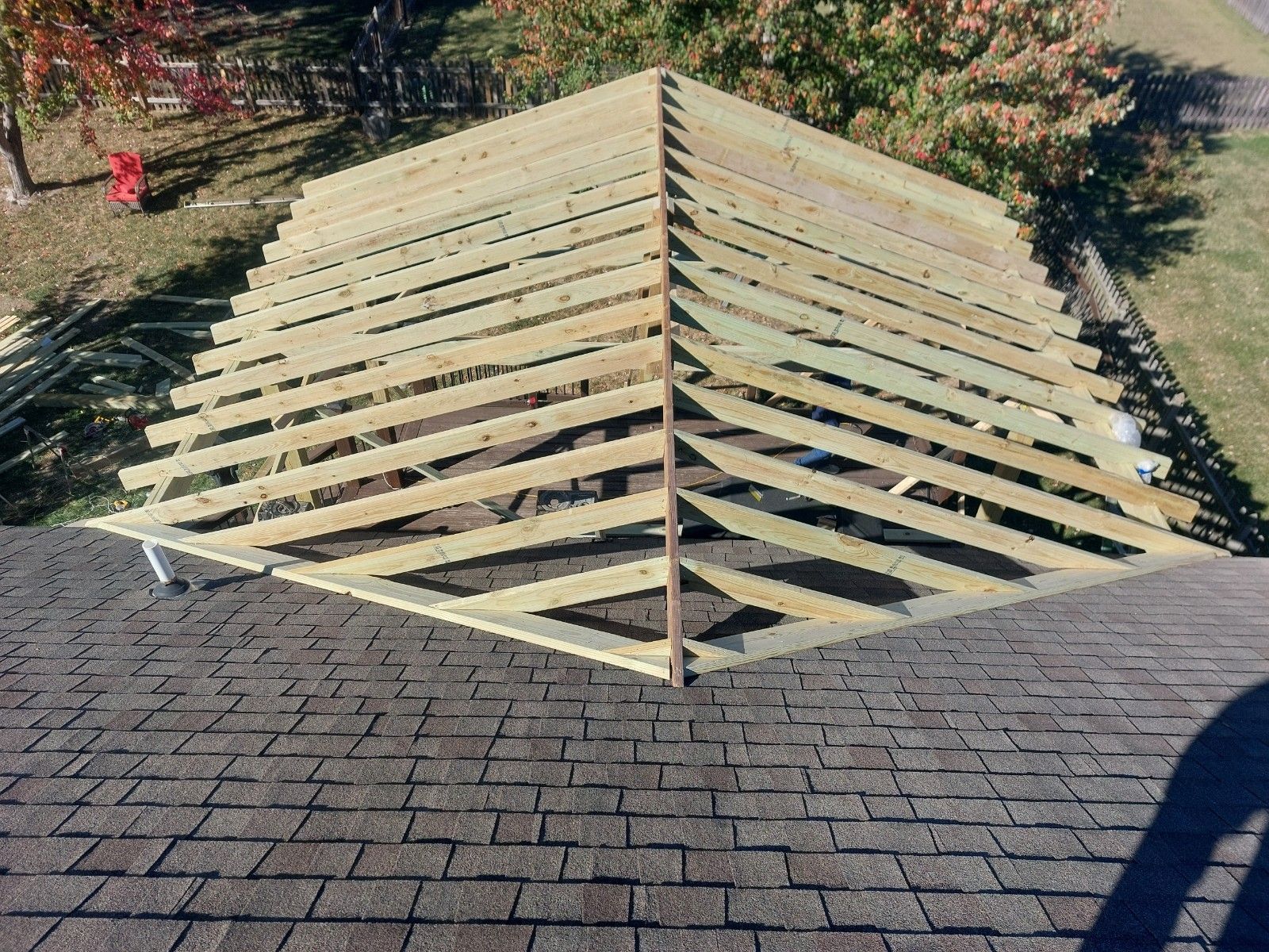 Roof under construction with exposed wooden rafters on a shingled house roof