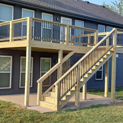 Apartment balcony with wooden exterior staircase and railings leading to an upper deck.