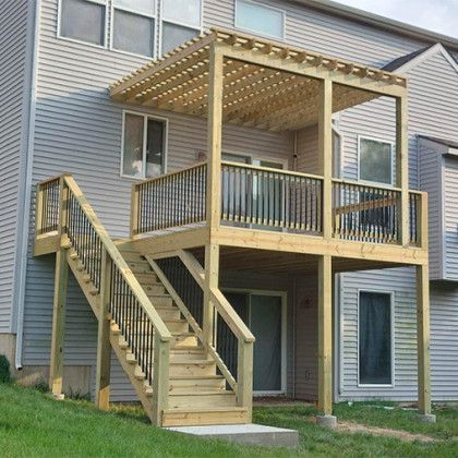 Back deck and staircase on a gray house with a covered patio and wooden railings