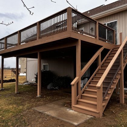 Raised wooden deck with stairs and railing attached to a house, viewed from below