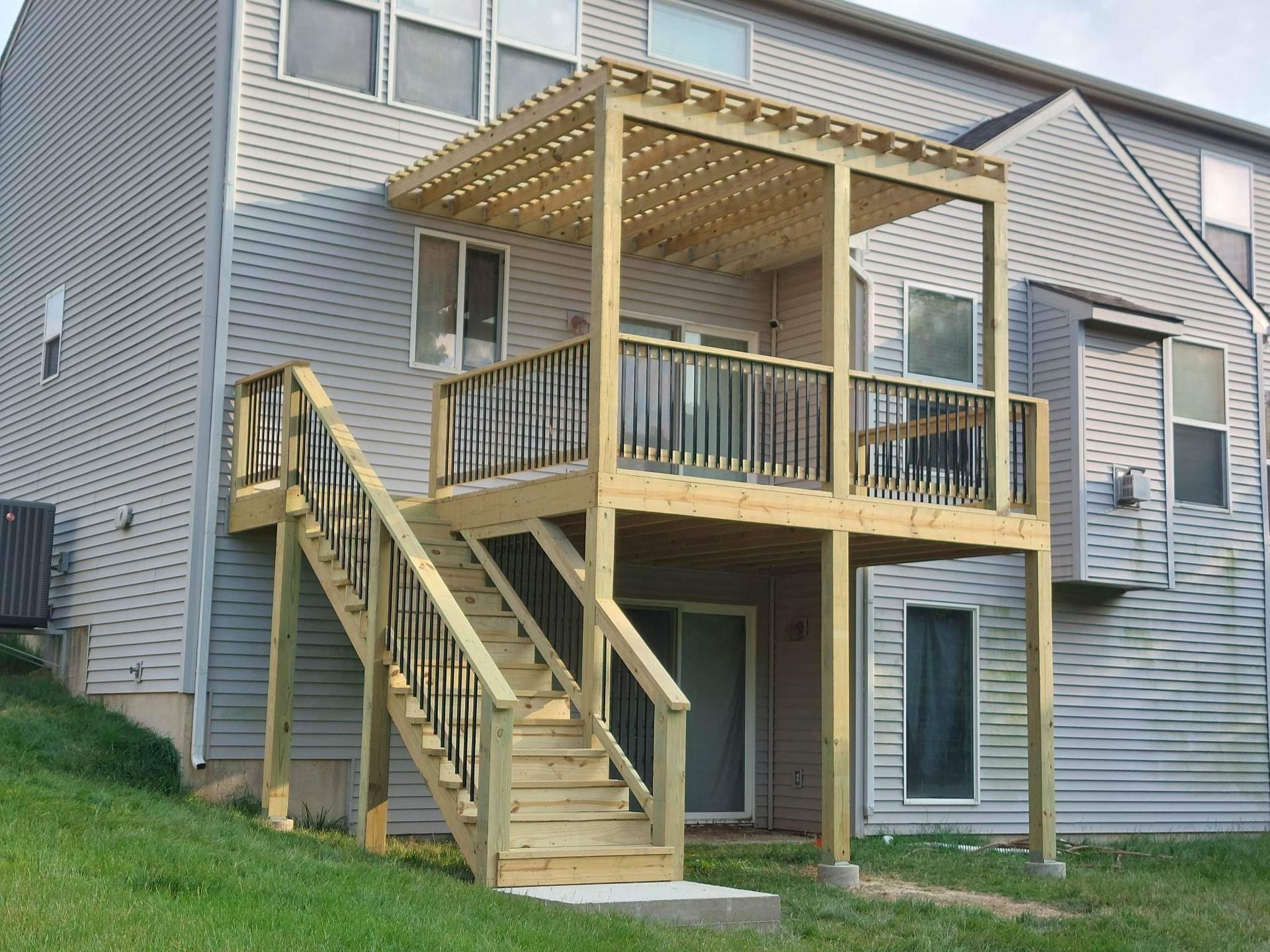 Wooden accessibility ramp and covered porch attached to a gray apartment building