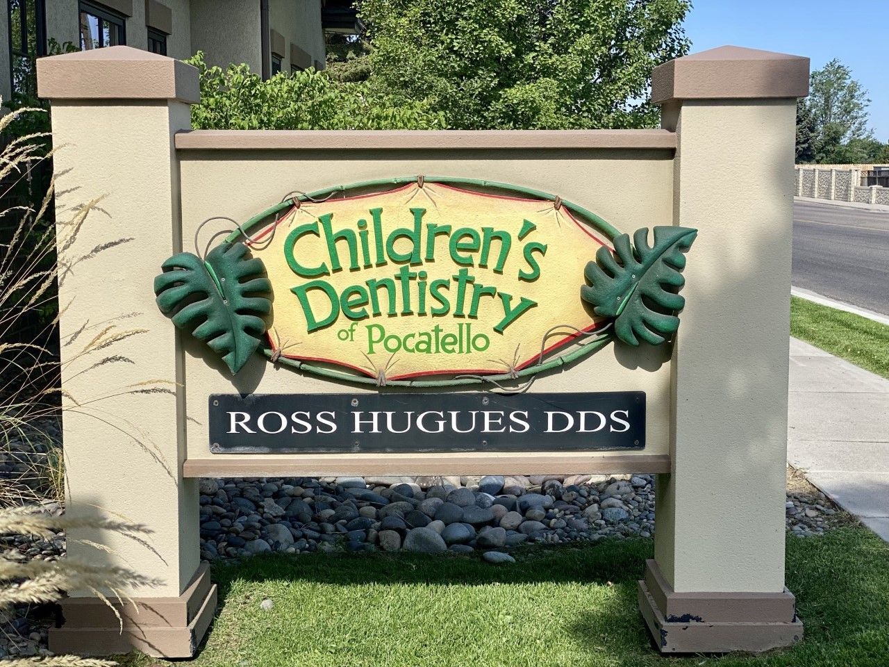 Sign for Children's Dentistry of Pocatello, green text and leaves on a tan background, with
