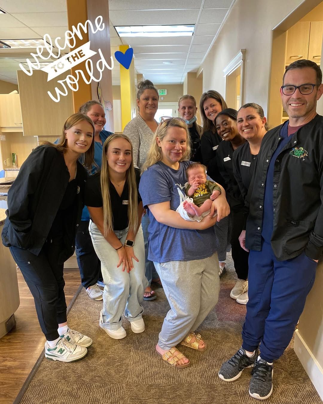 Medical staff and new mother holding newborn baby in a hallway. 
