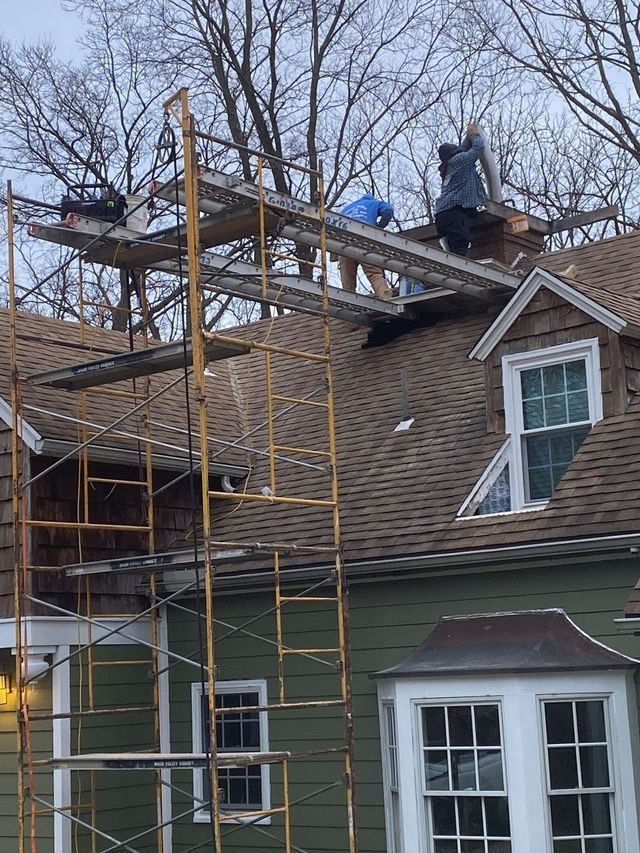 A group of people are working on the roof of a house.