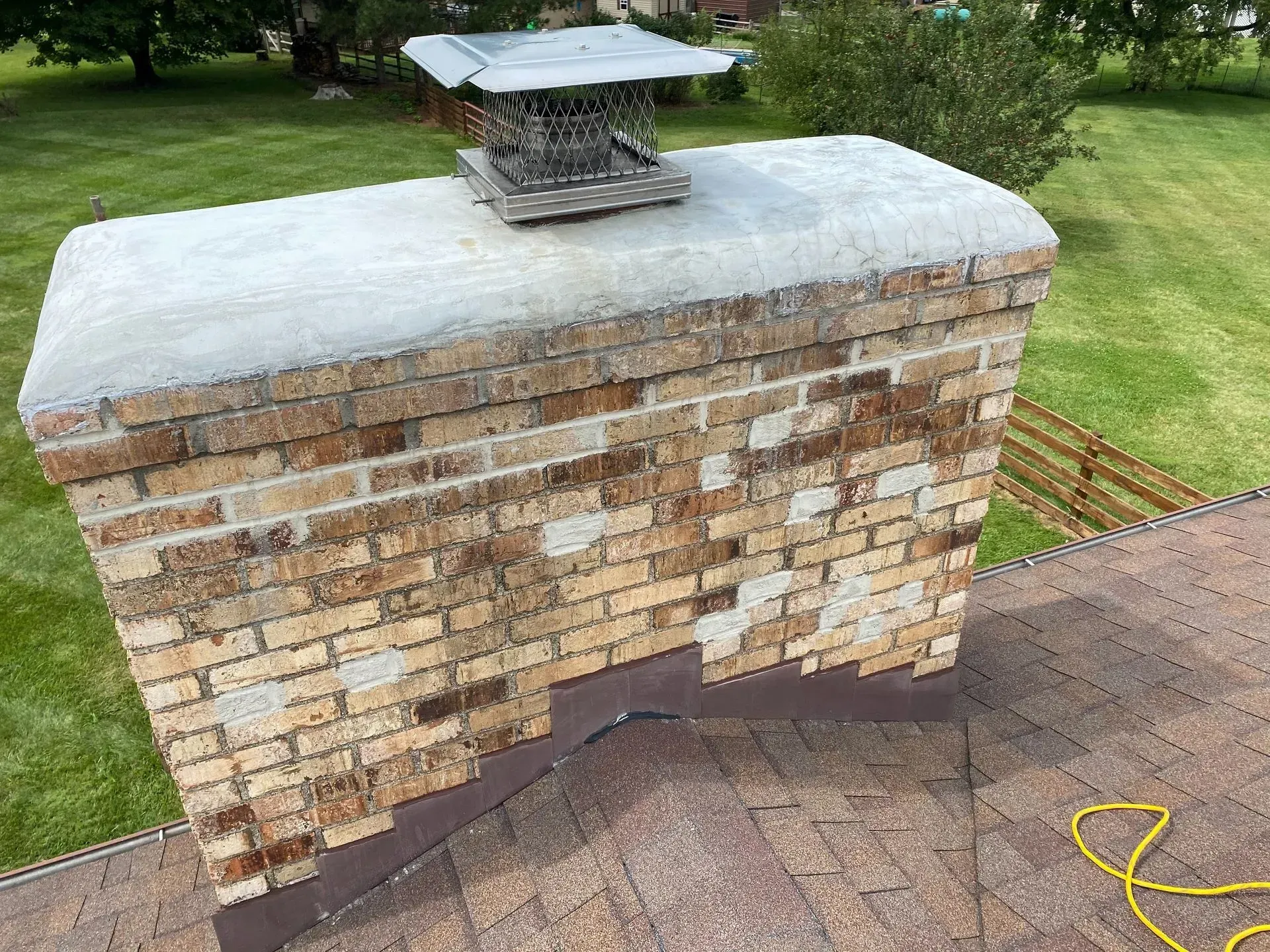 A brick chimney is sitting on top of a roof.