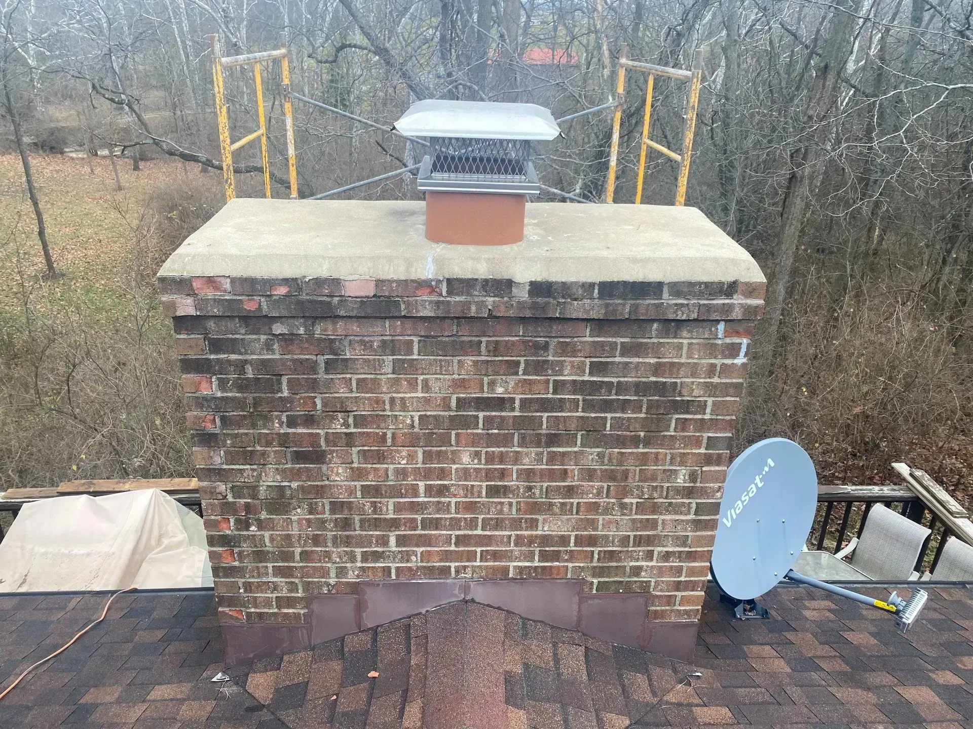 A brick chimney with a satellite dish on top of it.