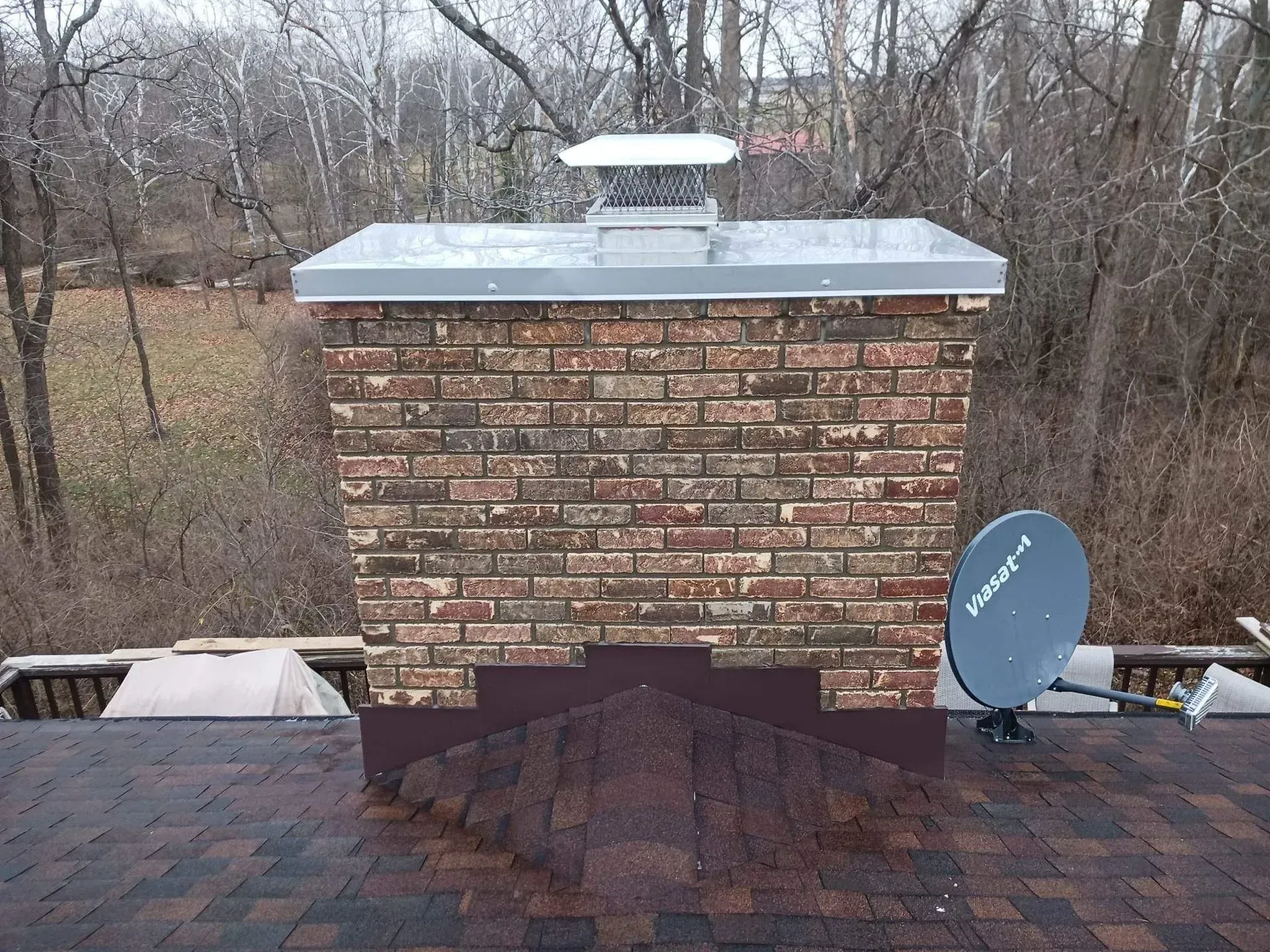 A brick chimney with a satellite dish on top of it