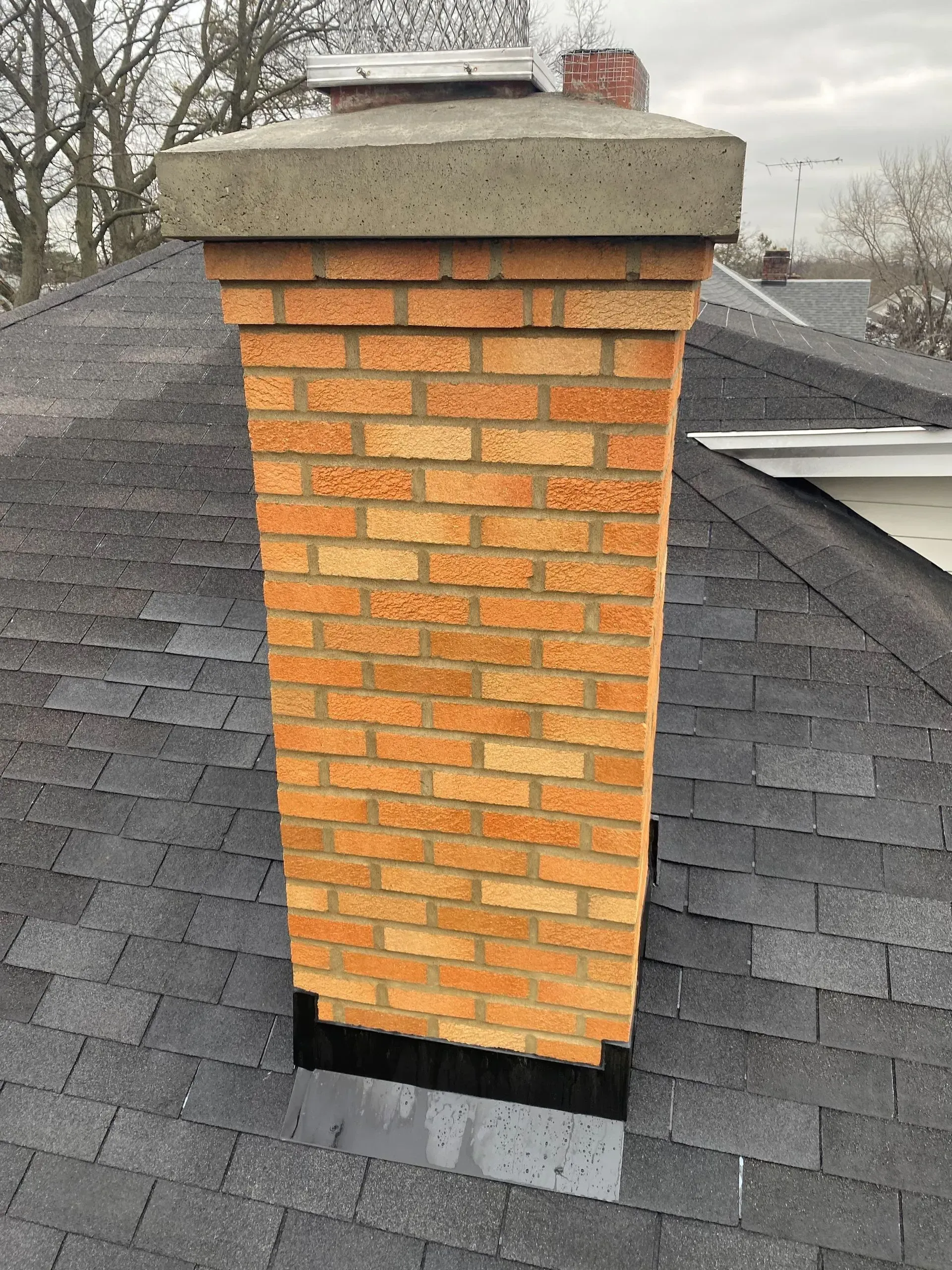 A brick chimney is sitting on top of a roof.