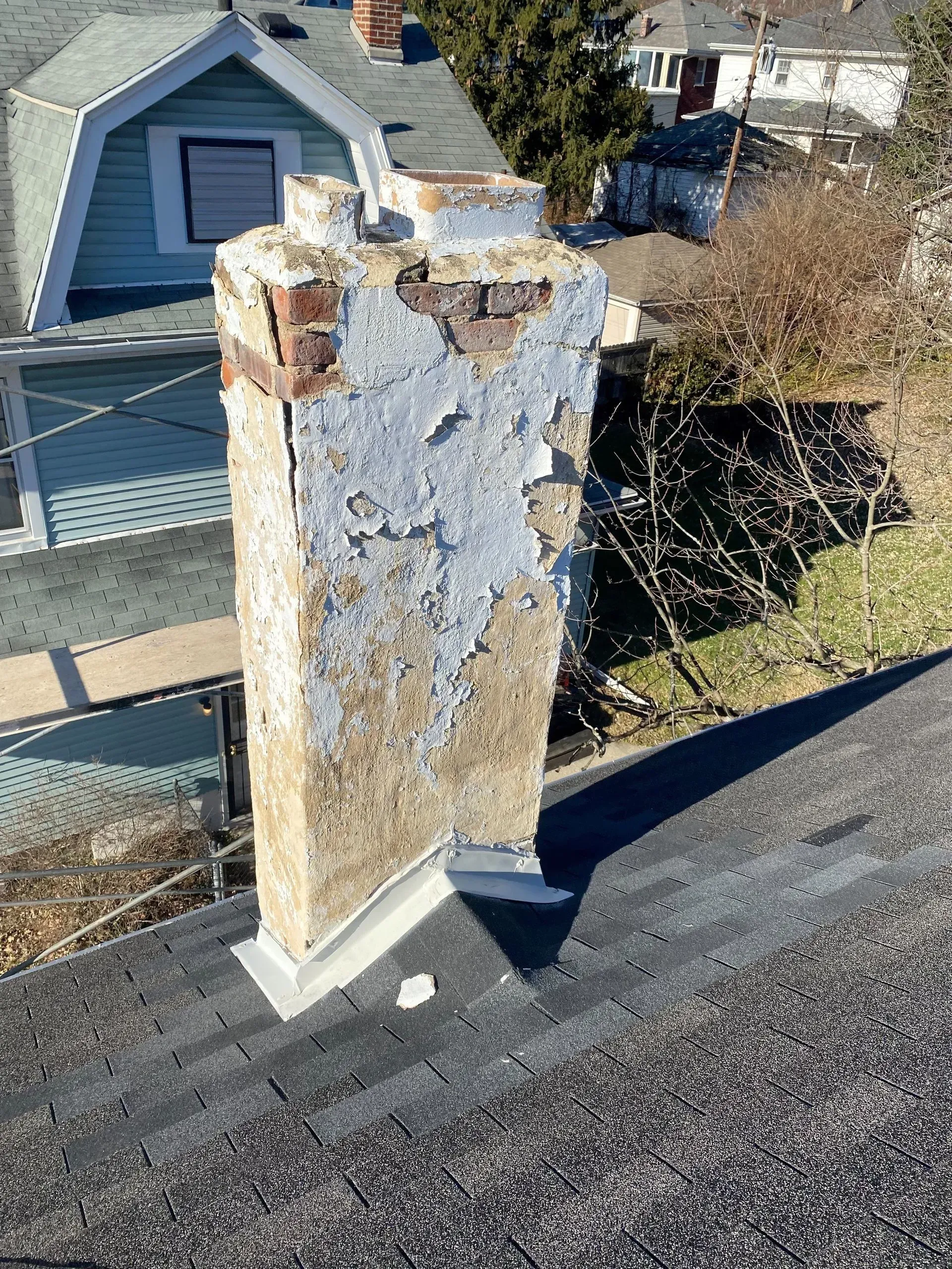 A chimney is sitting on top of a roof next to a house.