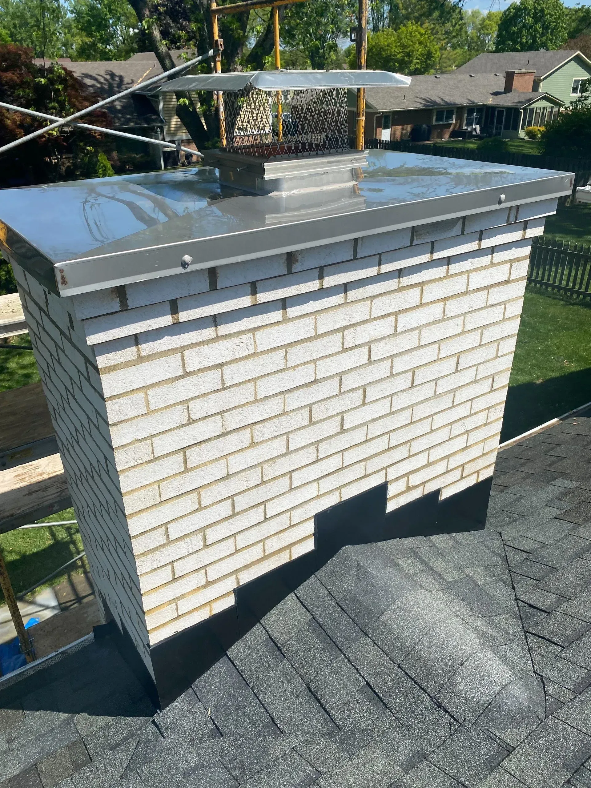 A white brick chimney is sitting on top of a roof.