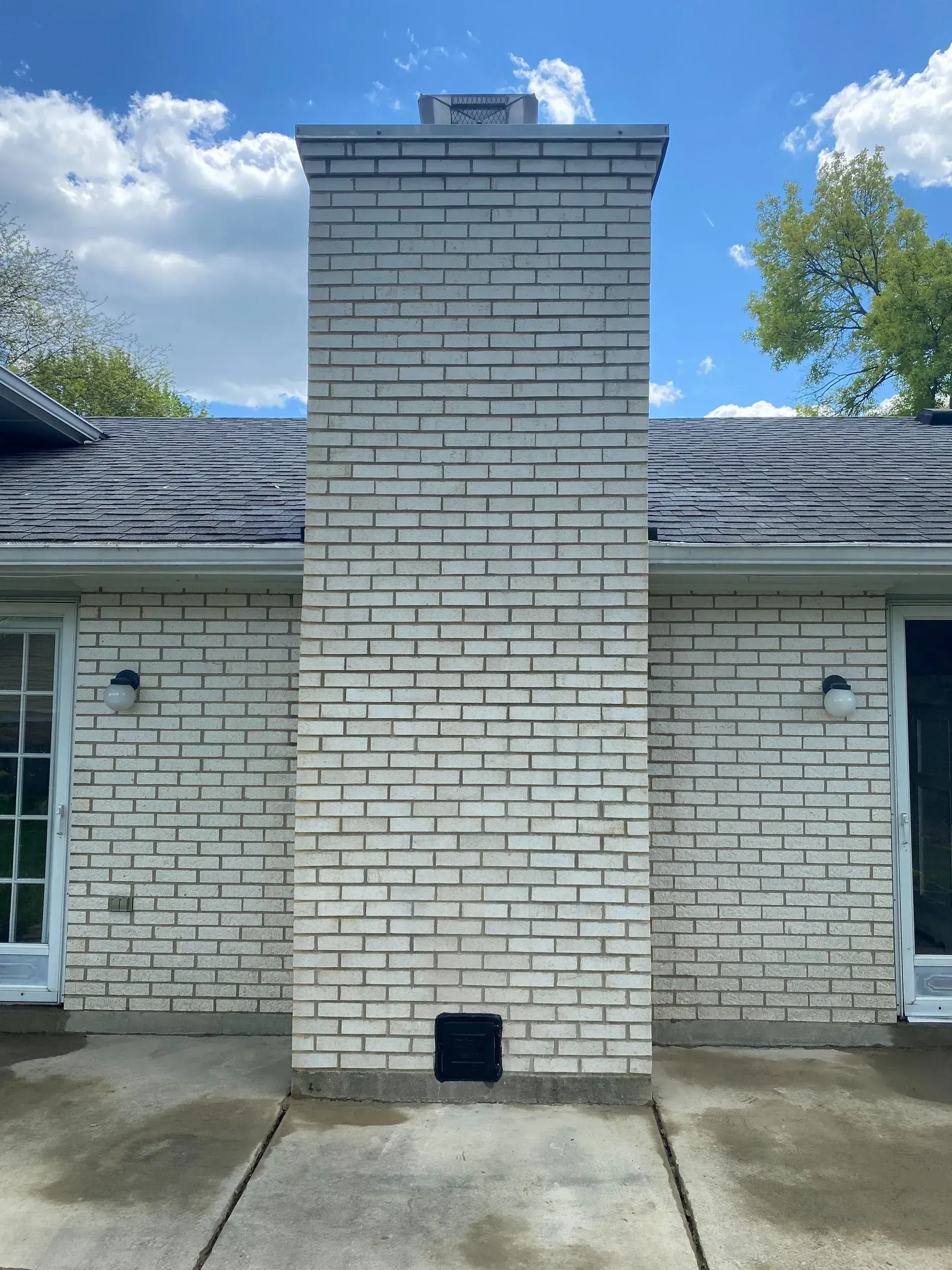 A white brick chimney on the side of a house.