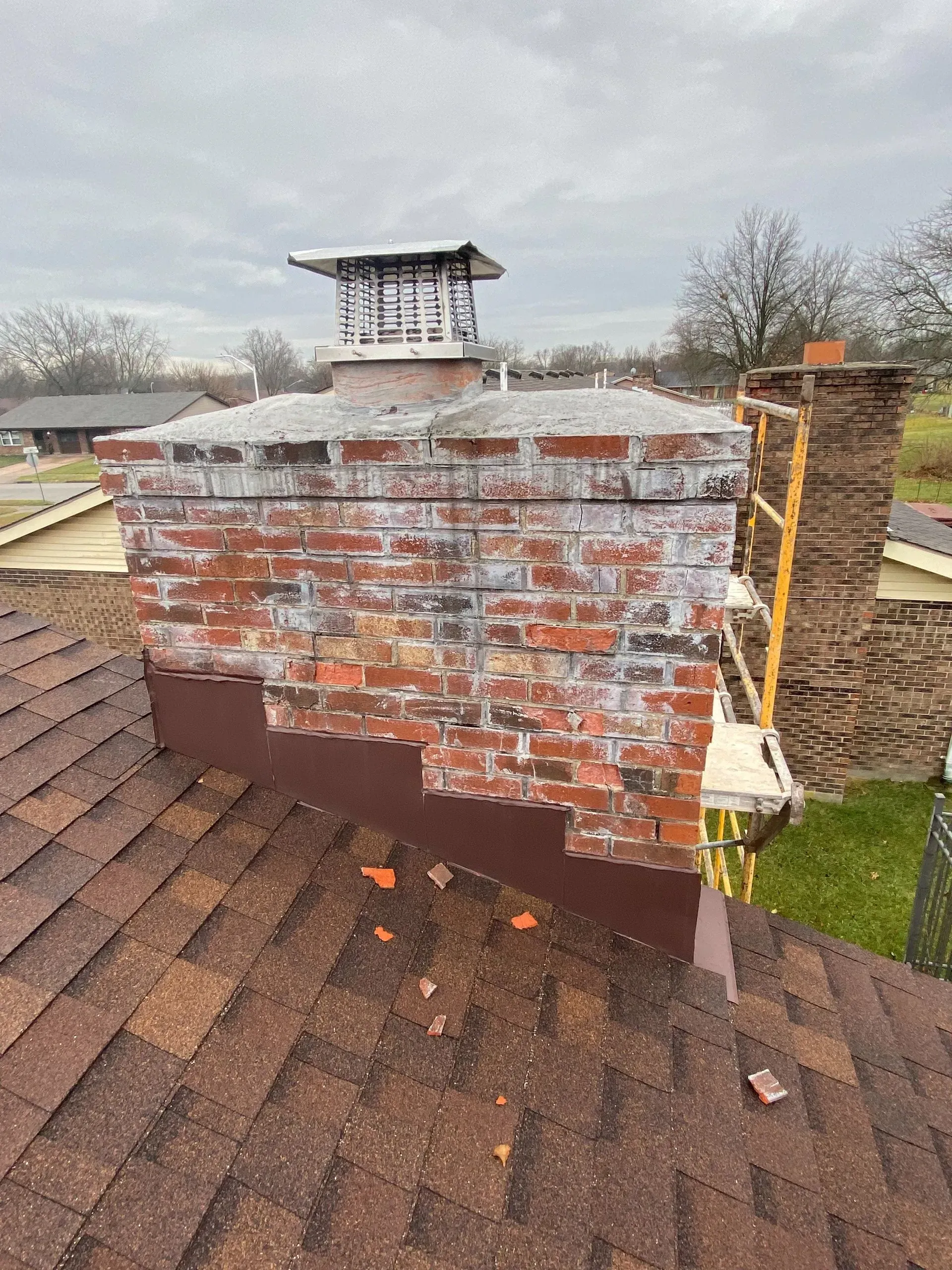 A brick chimney is sitting on top of a roof.