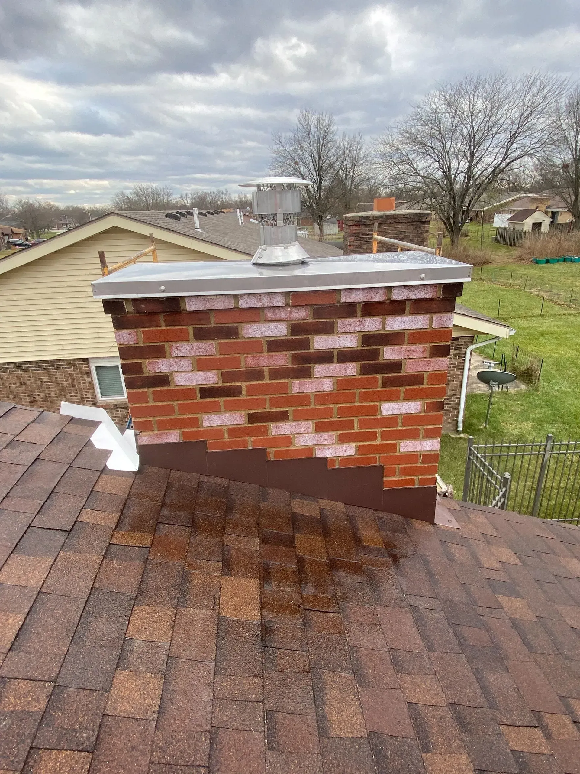 A brick chimney is sitting on top of a roof.