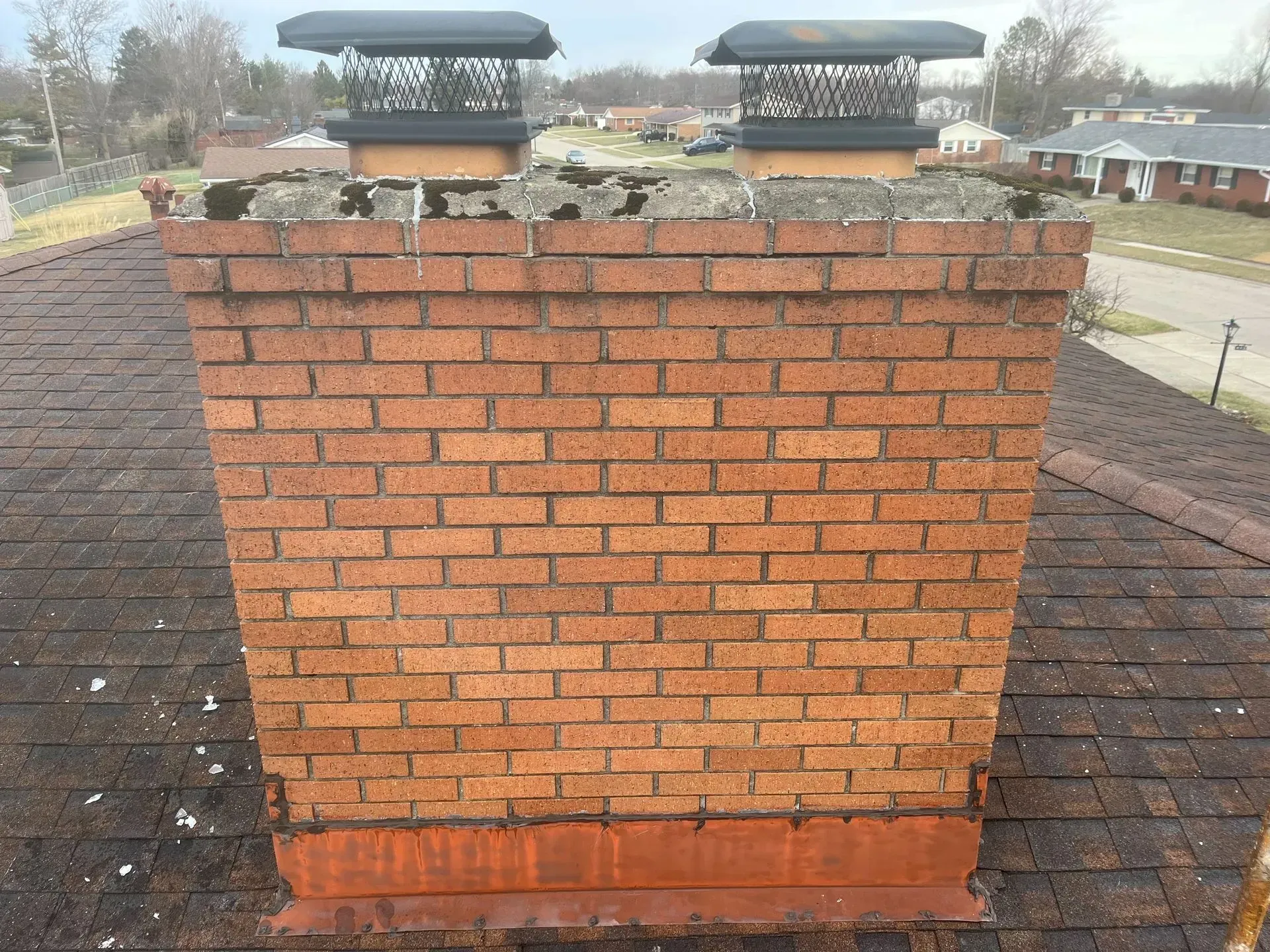 A brick chimney is sitting on top of a roof.