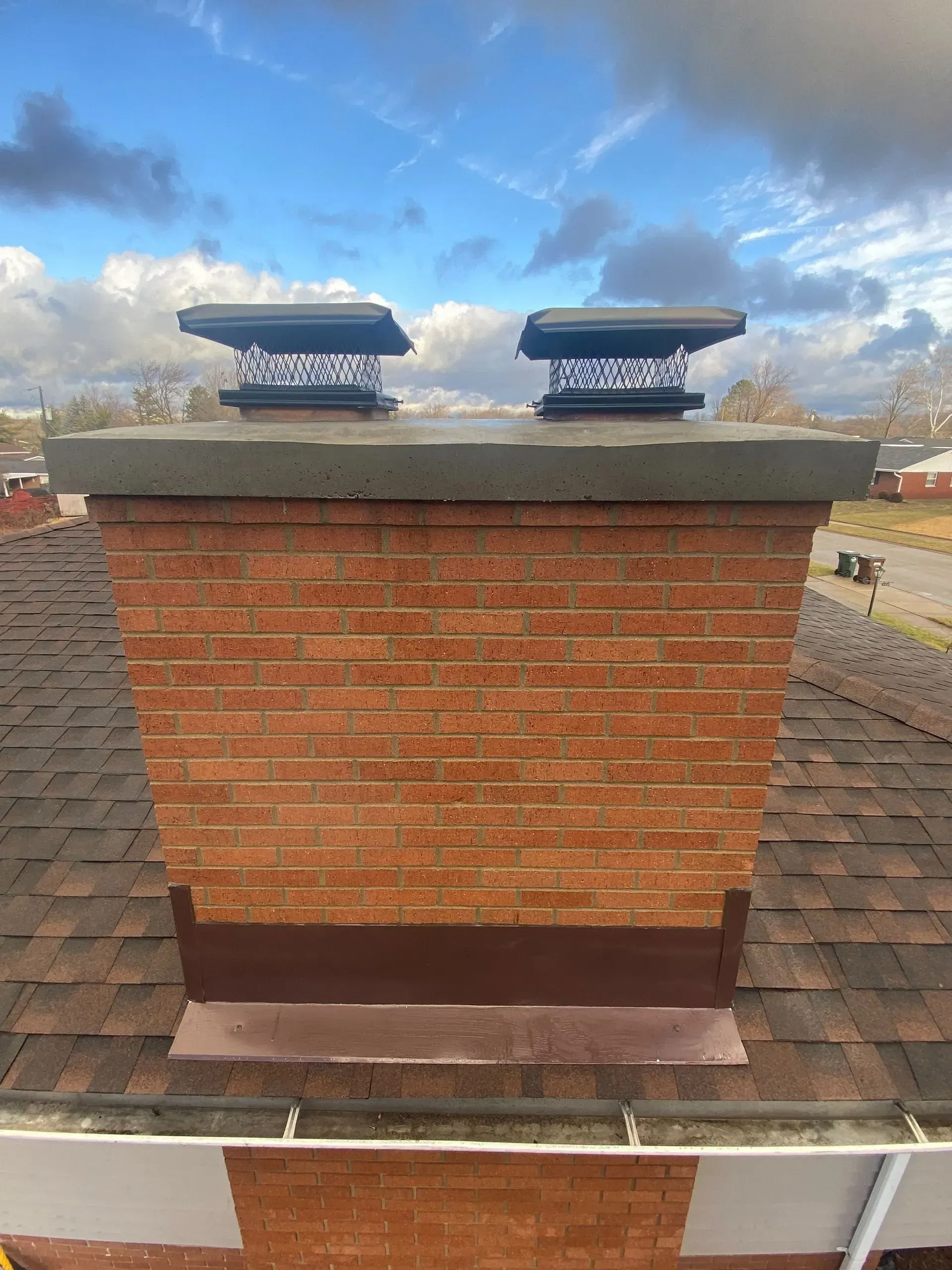 A brick chimney on top of a roof with a blue sky in the background.