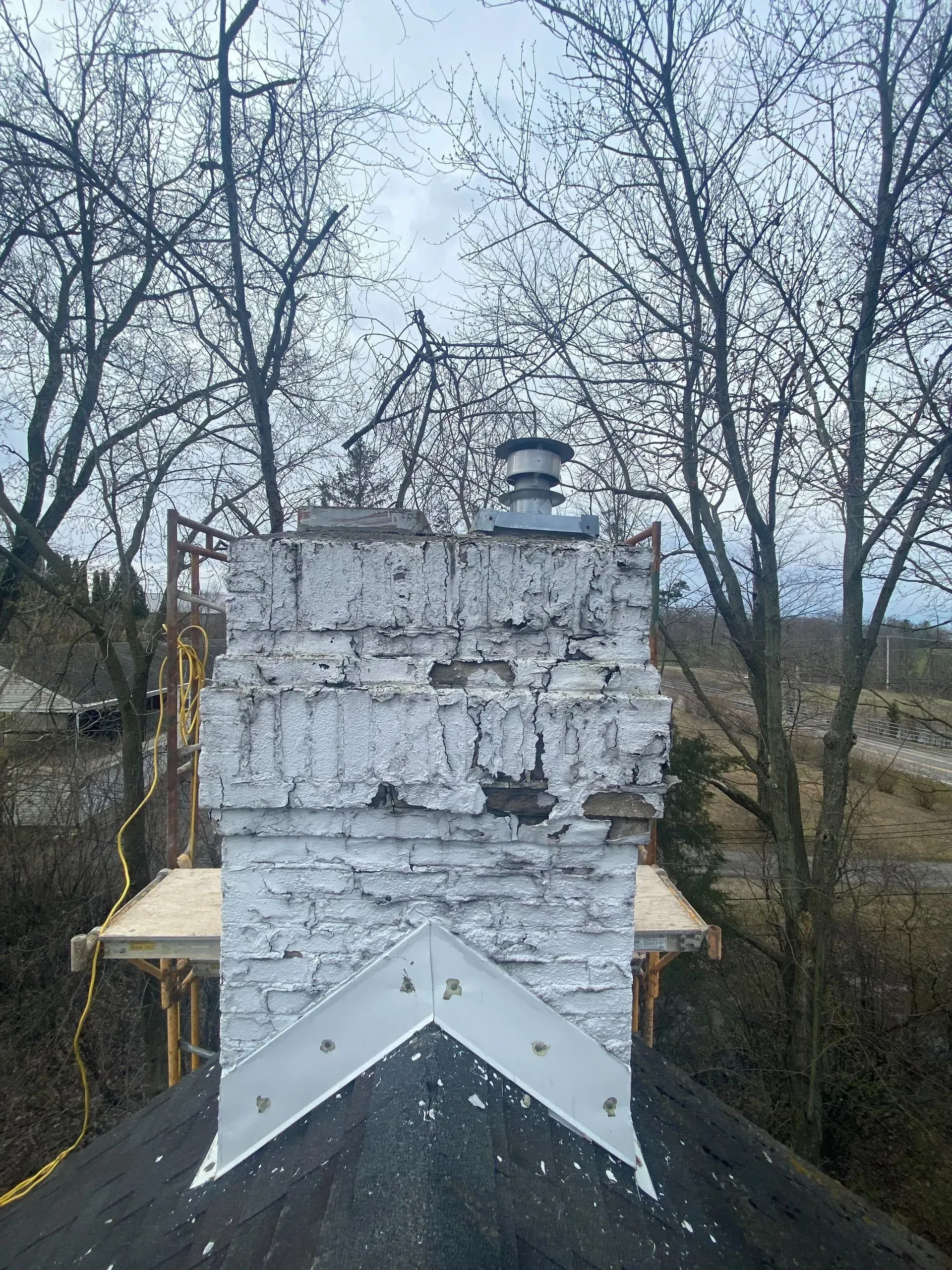 A white brick chimney is sitting on top of a black roof.