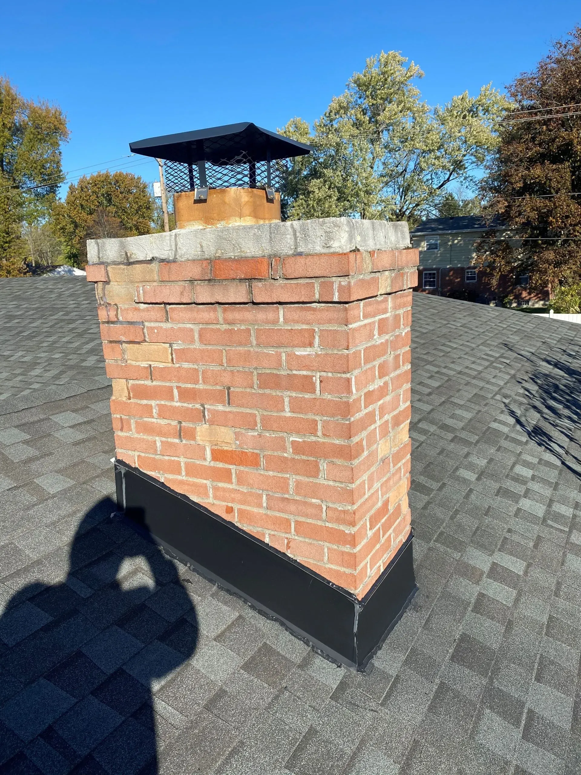 A brick chimney is sitting on top of a roof.