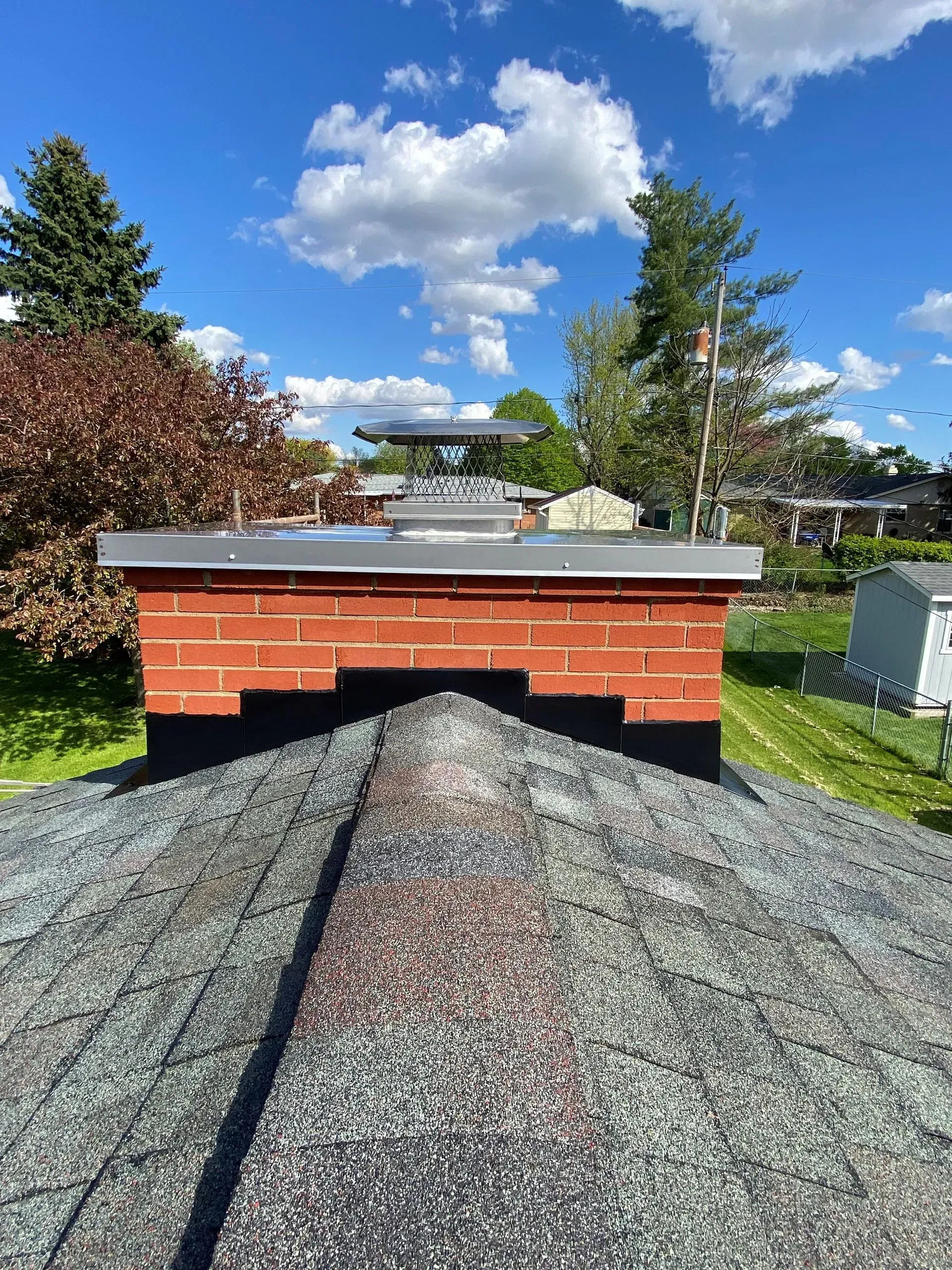 A brick chimney is sitting on top of a gravel roof.