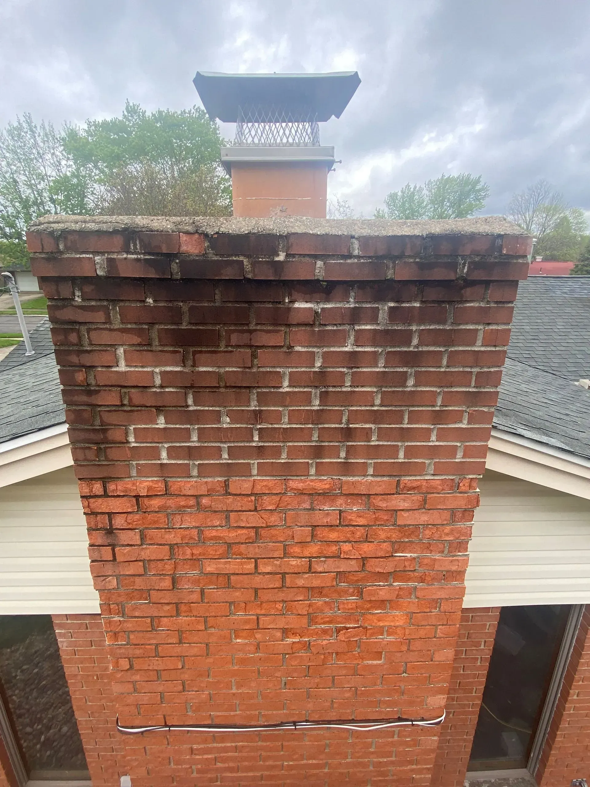 A brick chimney is sitting on top of a brick building.