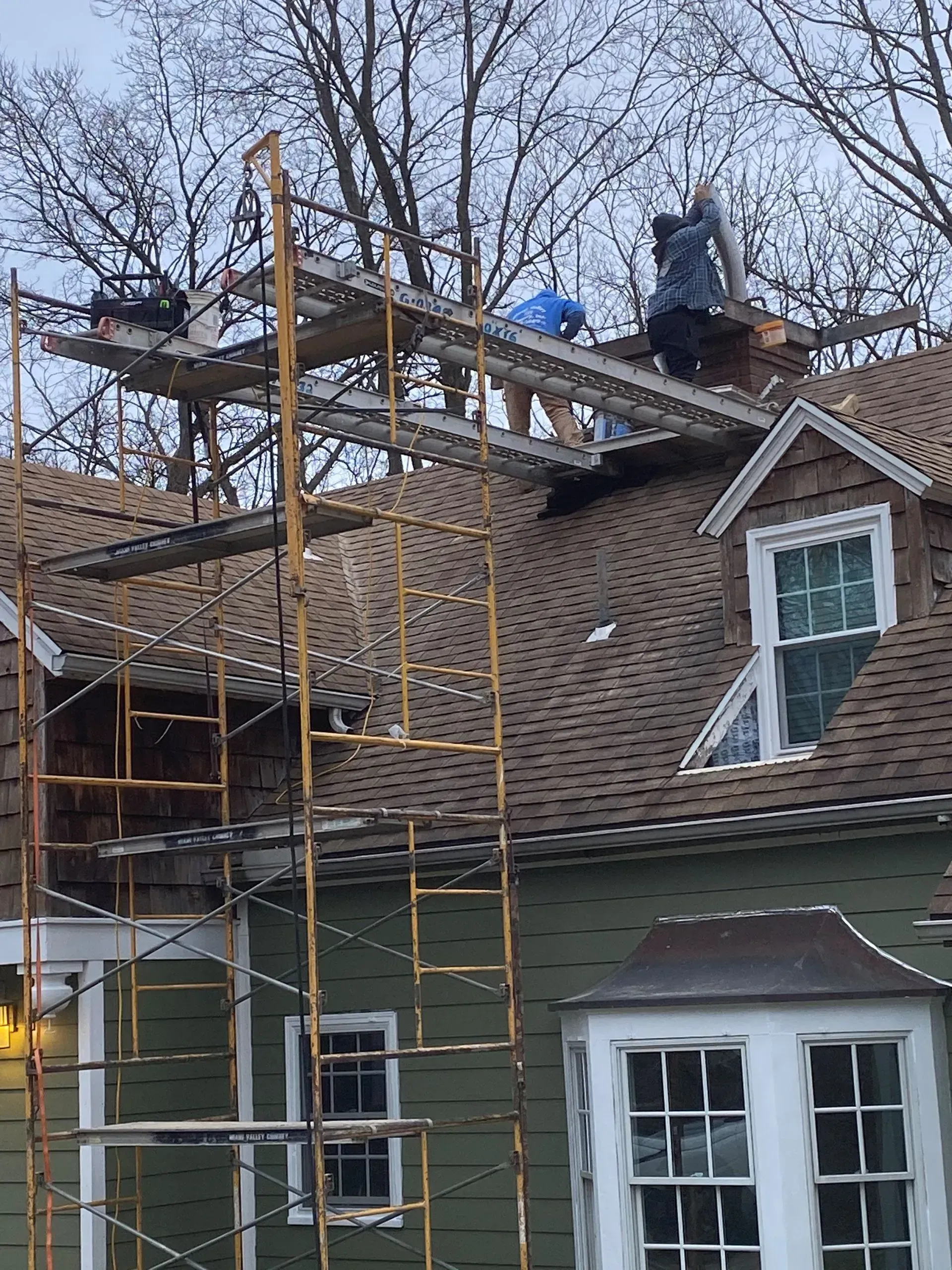 Two men are working on the roof of a house.