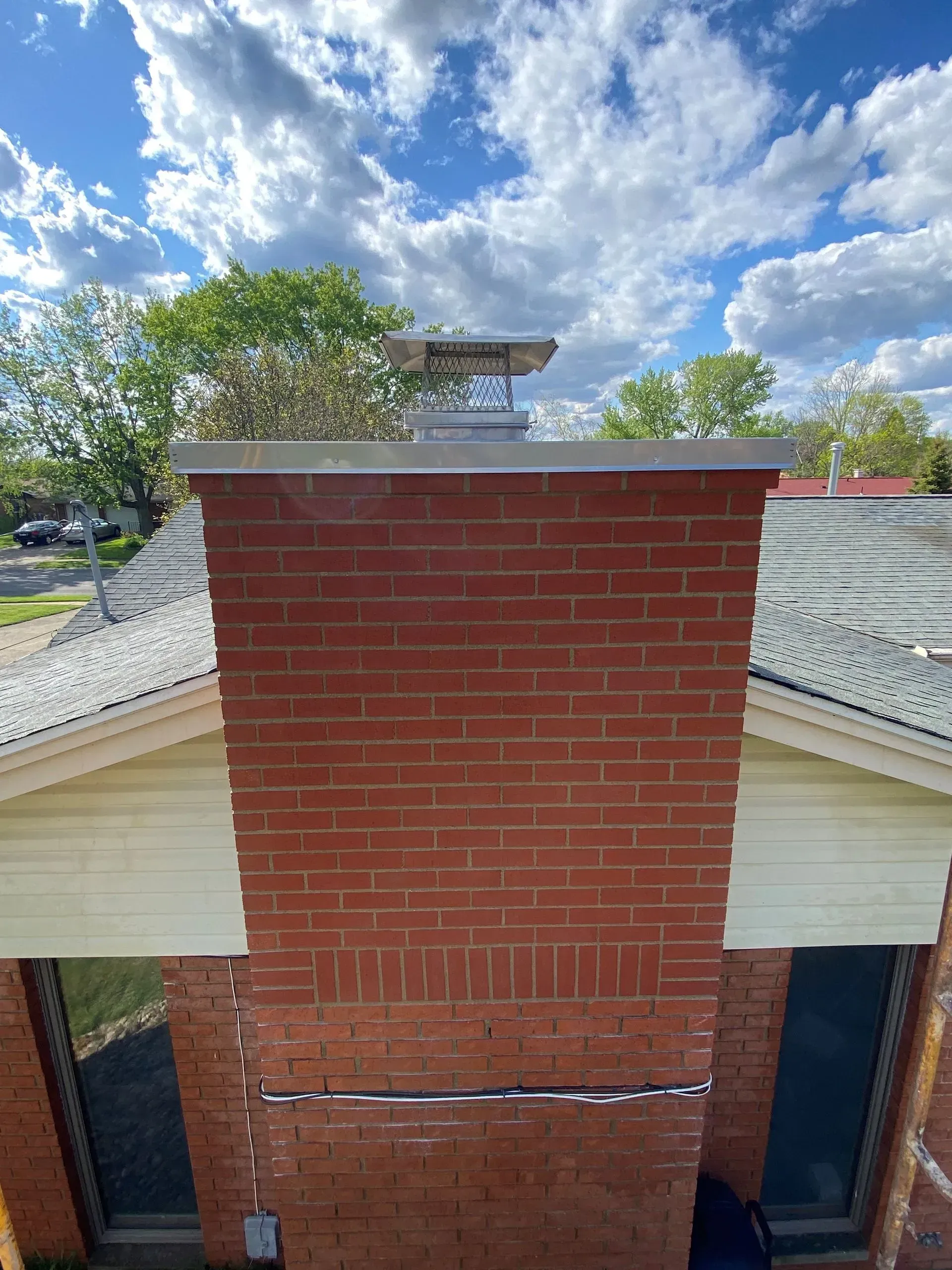 A brick chimney is on the roof of a house.