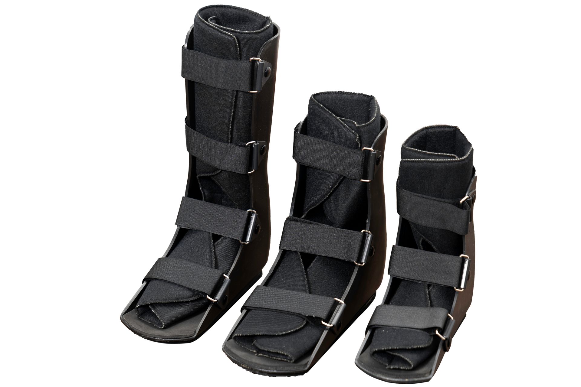 Tres botas médicas para caminar de color negro, de diferentes alturas.