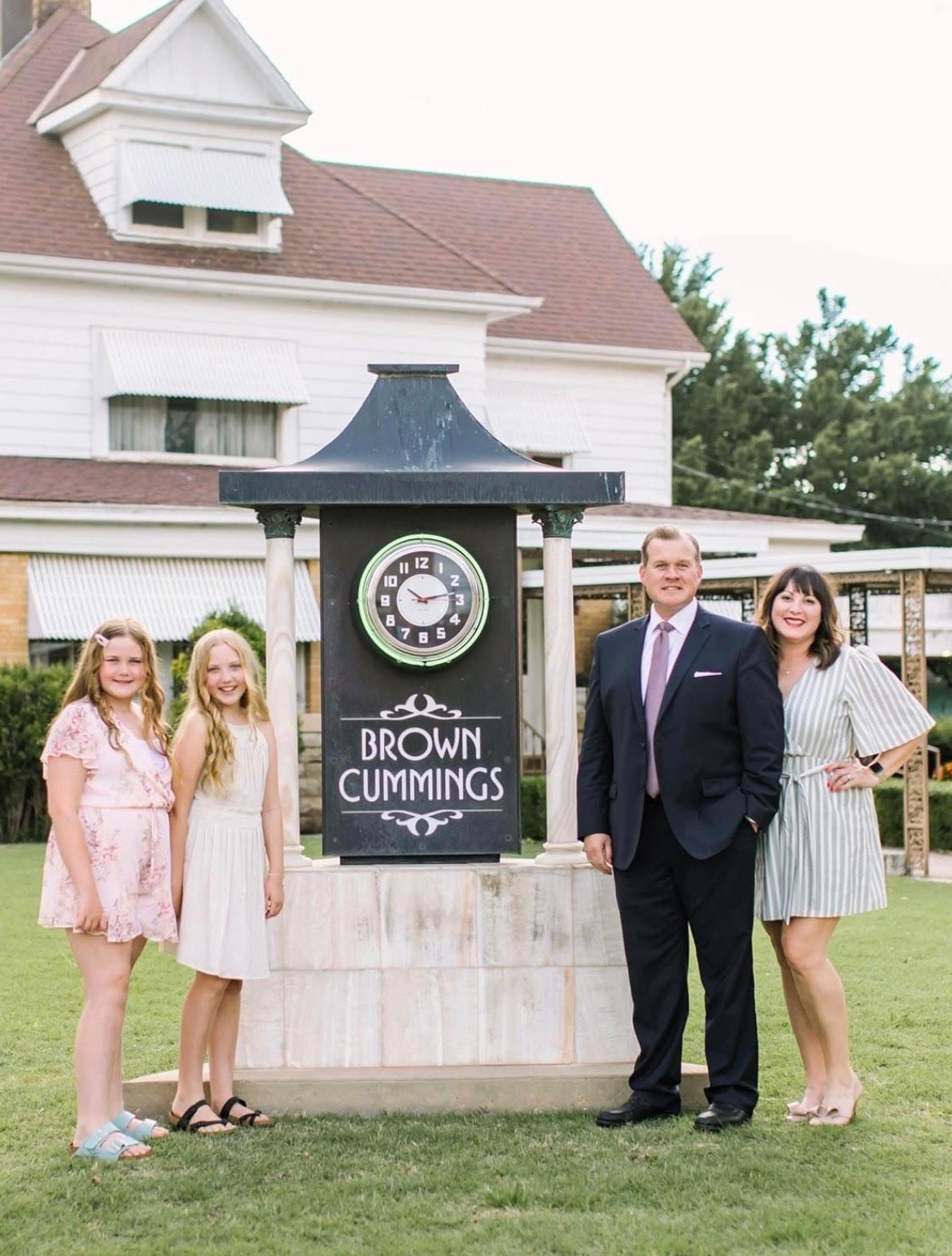 a family is standing in front of a sign that says brown cummings .