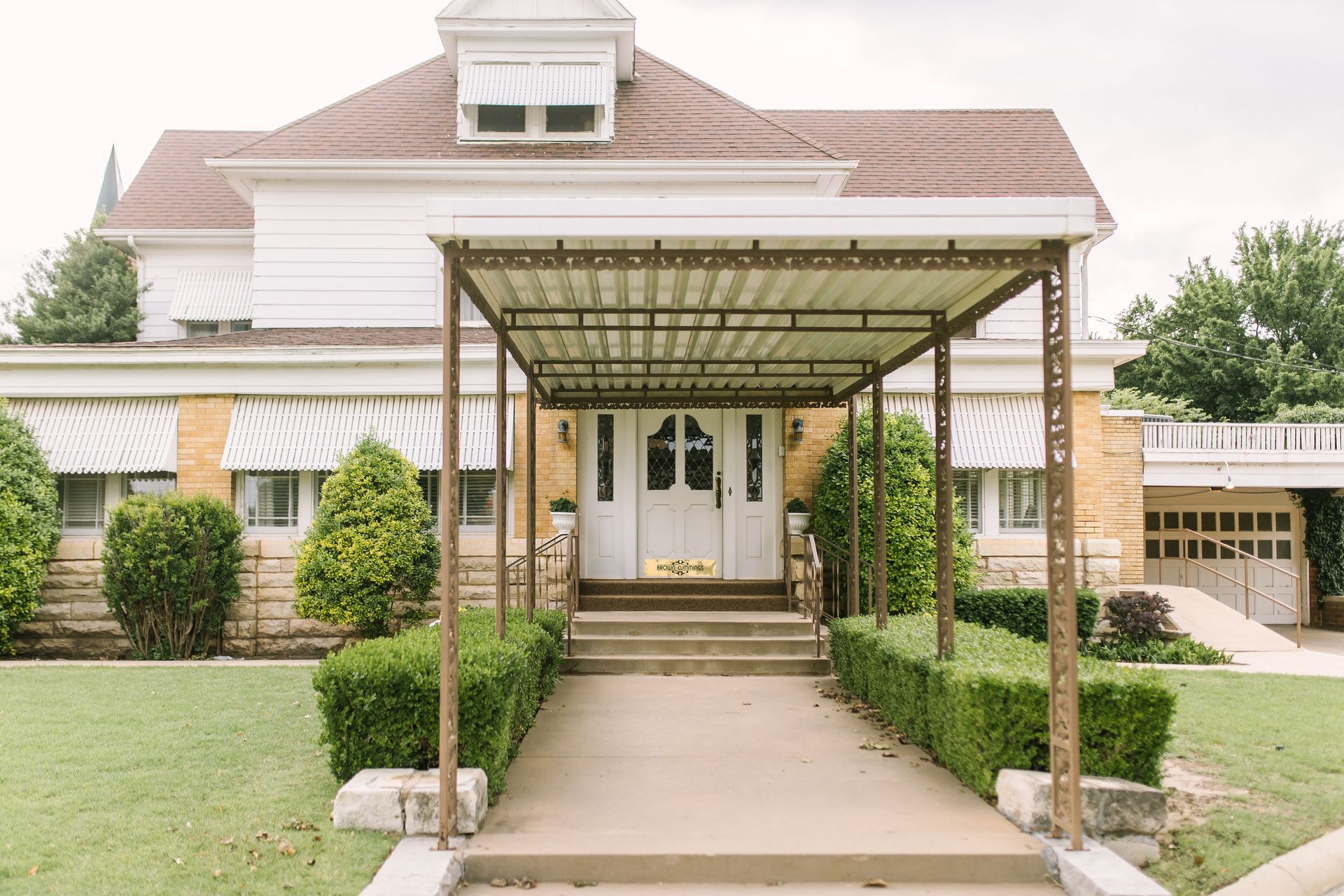 a large house with a covered walkway leading to the front door .
