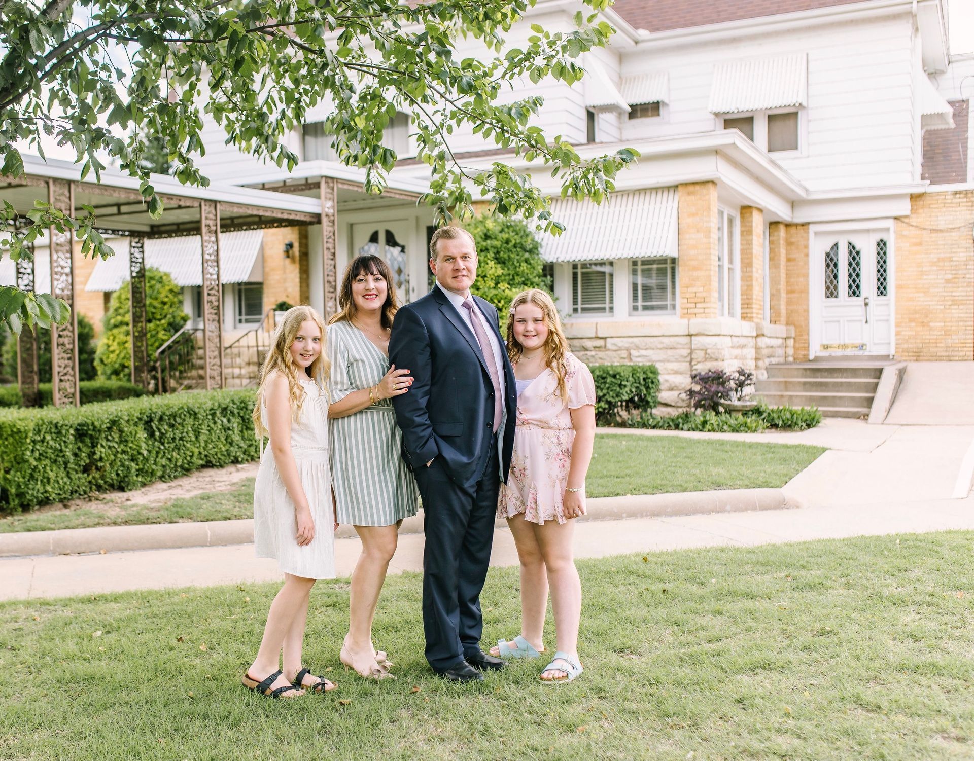a family is posing for a picture in front of a house .