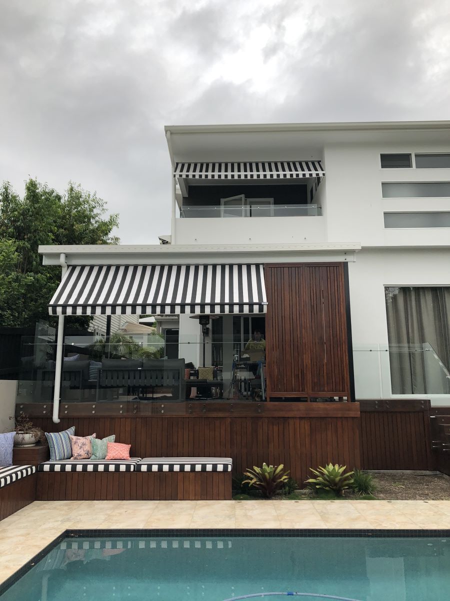 A White House With a Striped Awning Over a Swimming Pool — Homemakers Lifestyle In Maroochydore, QLD