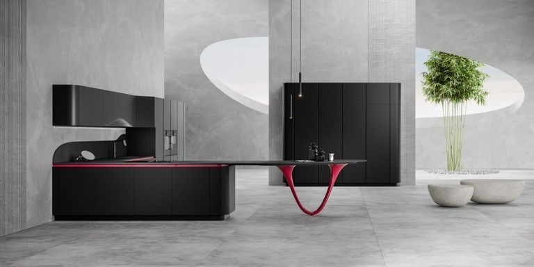 Una cucina moderna con mobili neri e un tavolo rosso.