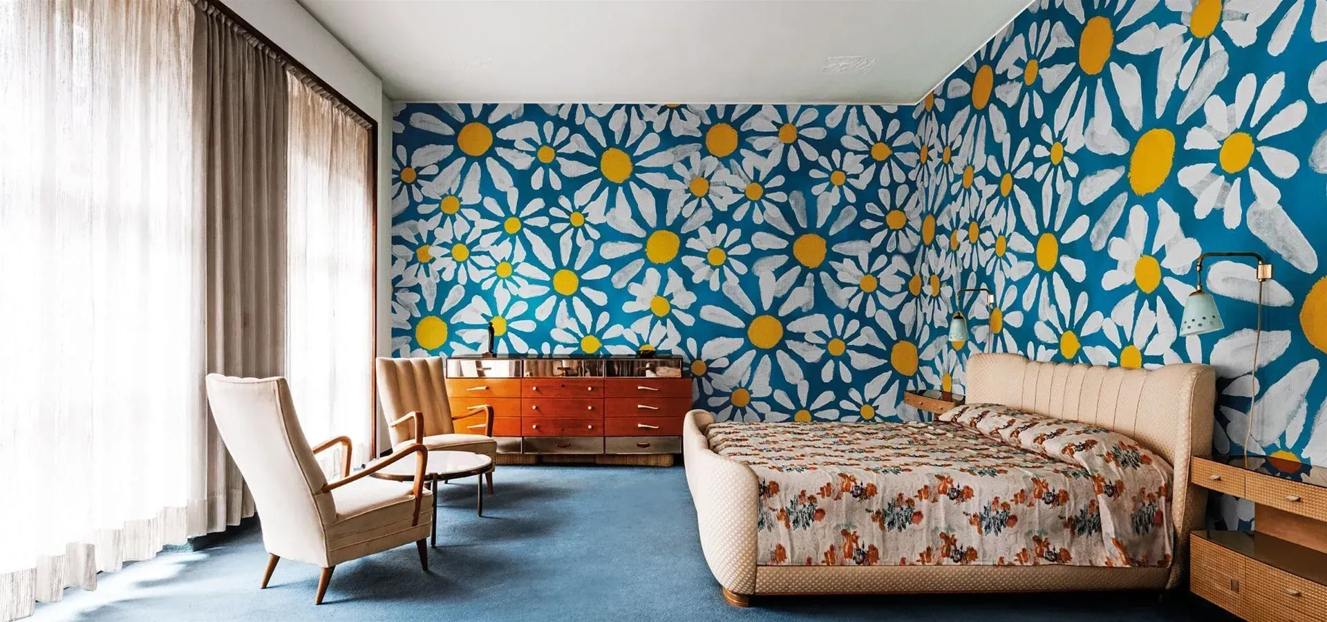 Una camera da letto con un letto e delle sedie e una parete con delle margherite dipinte sopra