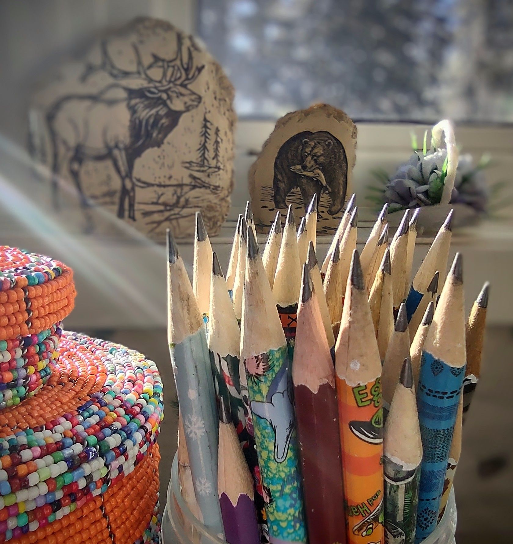 a bunch of pencils in a jar with a deer on a pillow in the background
