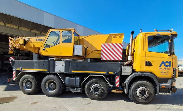 Quattro camion gialli dell'azienda parcheggiati fianco a fianco su un piazzale asfaltato sotto un cielo azzurro e limpido.
