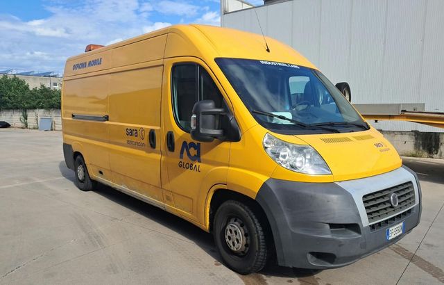 Quattro camion gialli dell'azienda parcheggiati fianco a fianco su un piazzale asfaltato sotto un cielo azzurro e limpido.