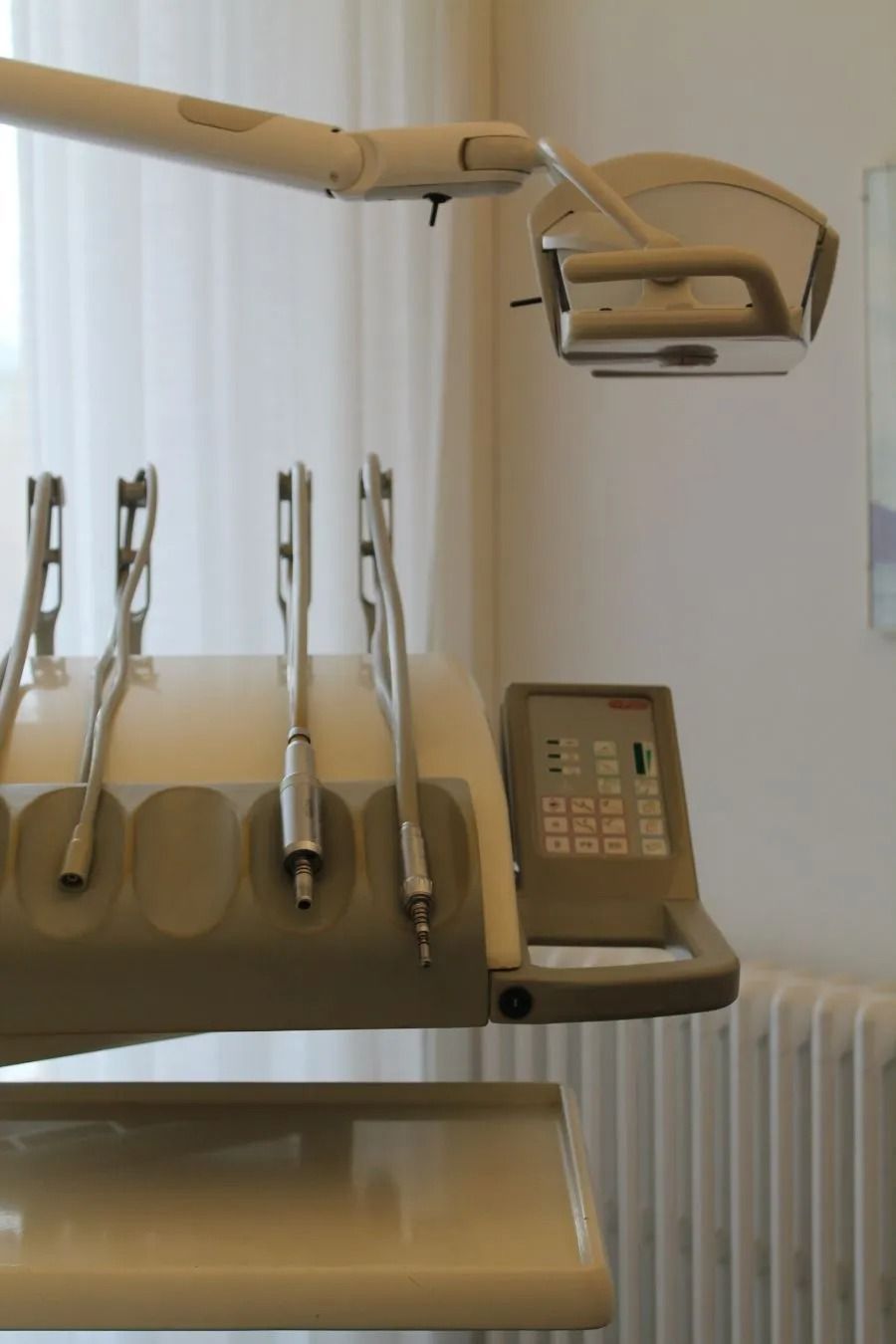 Poltrona odontoiatrica con lampada a soffitto e vassoio porta-strumenti in una sala operatoria.