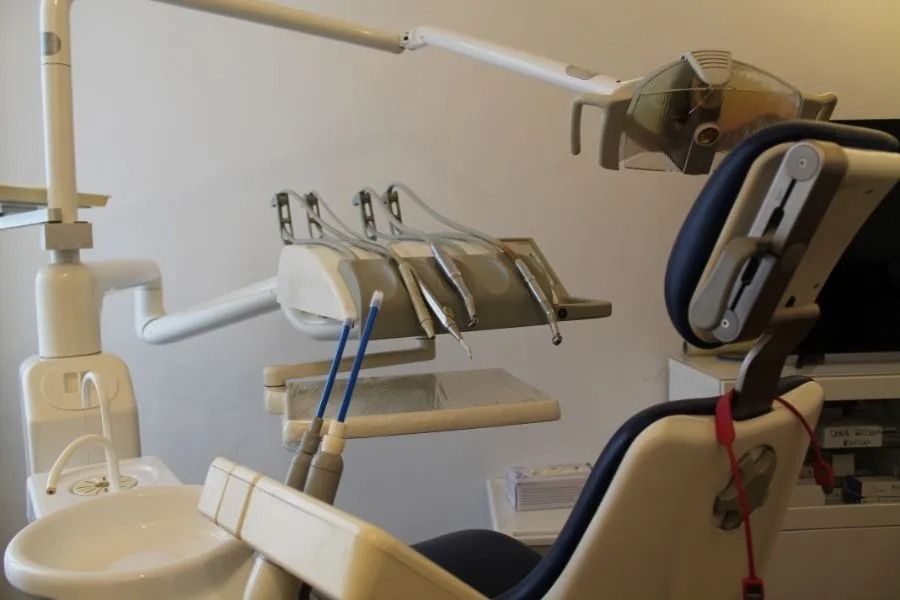 Poltrona odontoiatrica con lampada a soffitto e vassoi per strumenti in una sala operatoria.