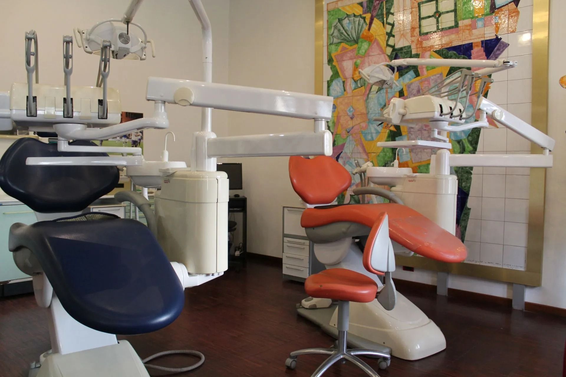 Sala per visite odontoiatriche con due poltrone, luci a soffitto e attrezzature dentistiche a parete.