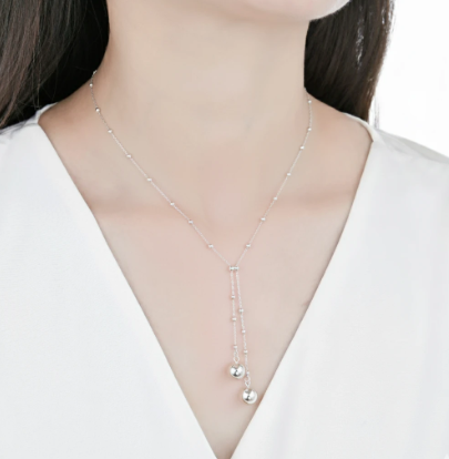 Collar de plata en forma de Y con pequeñas cuentas y dos grandes colgantes esféricos.