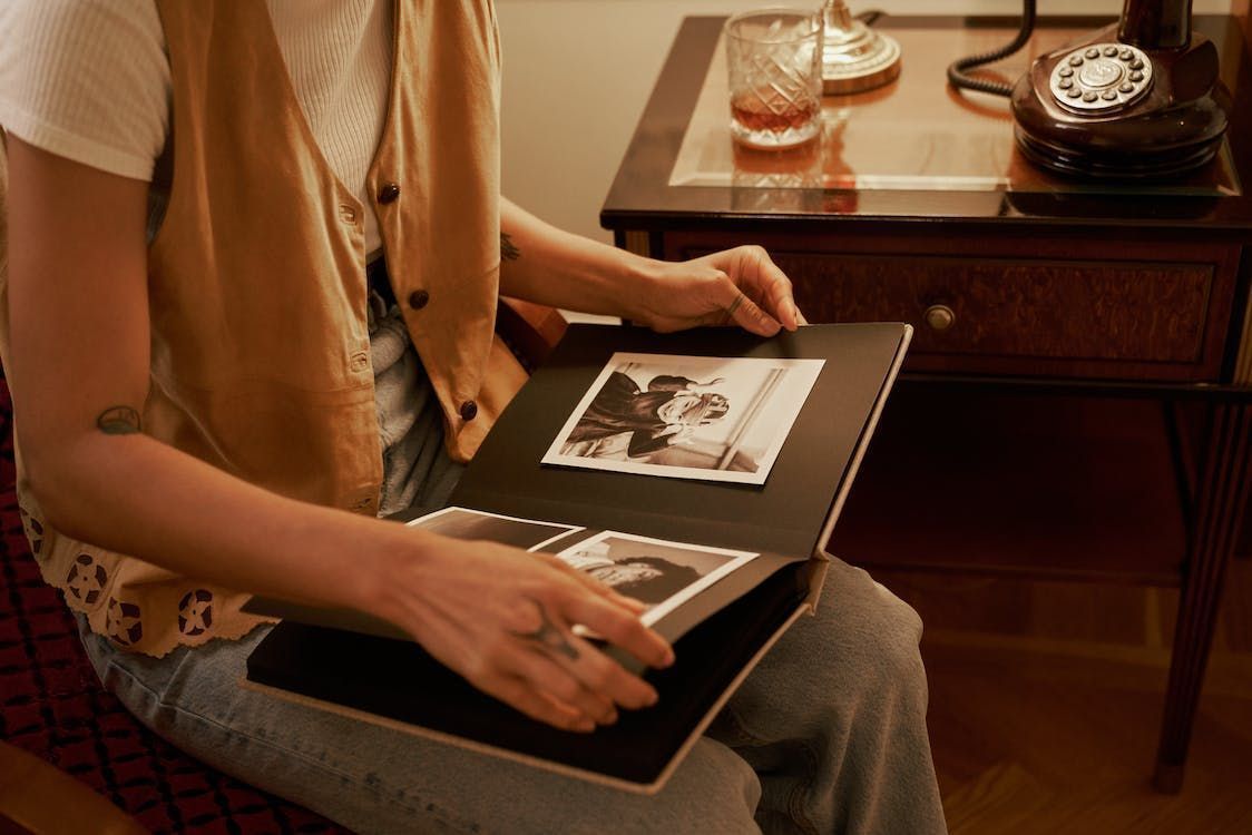 A man and a woman are sitting on a couch looking at a photo album.